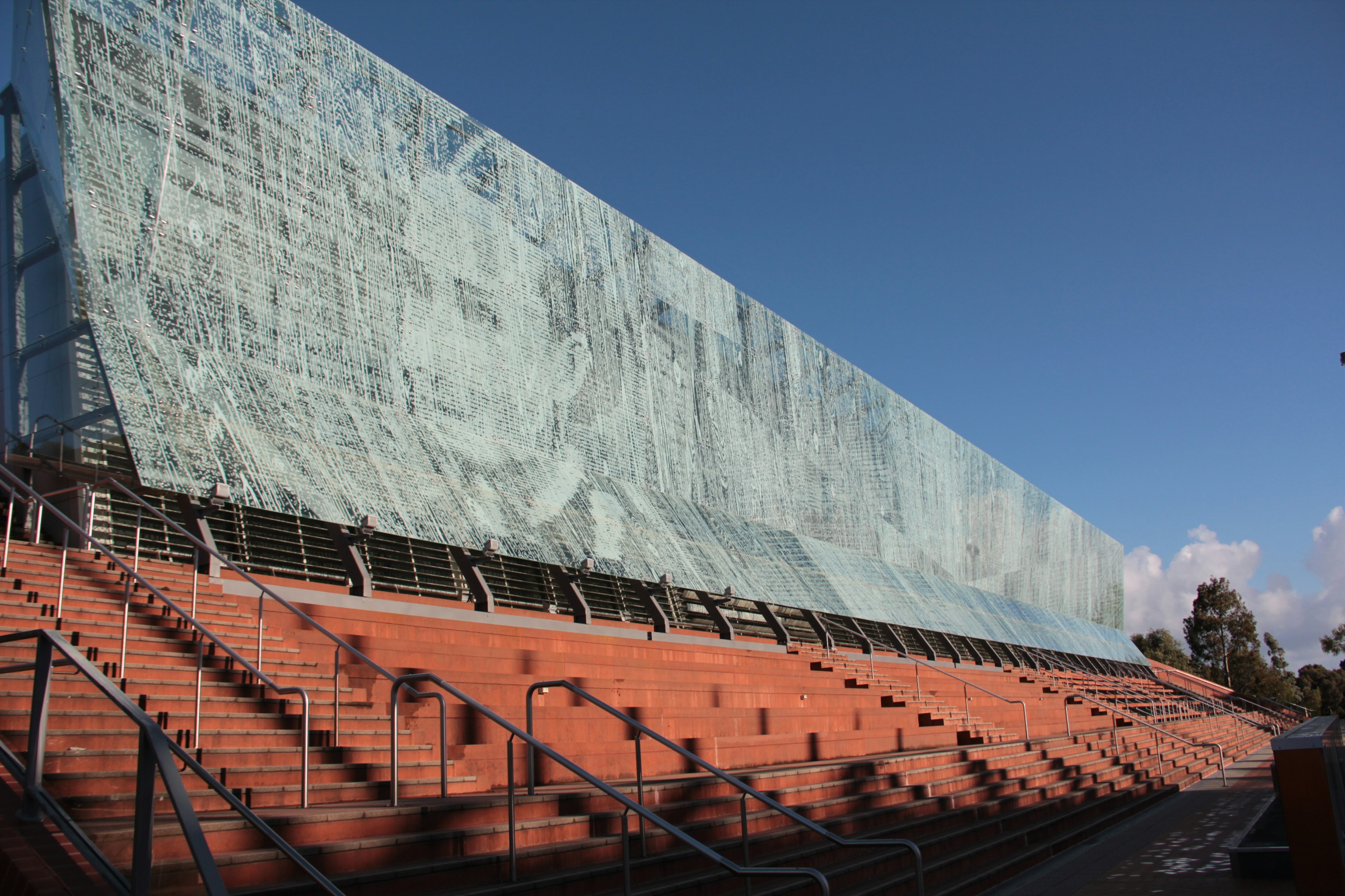 Exterior view of a building with a large mural and red staircases