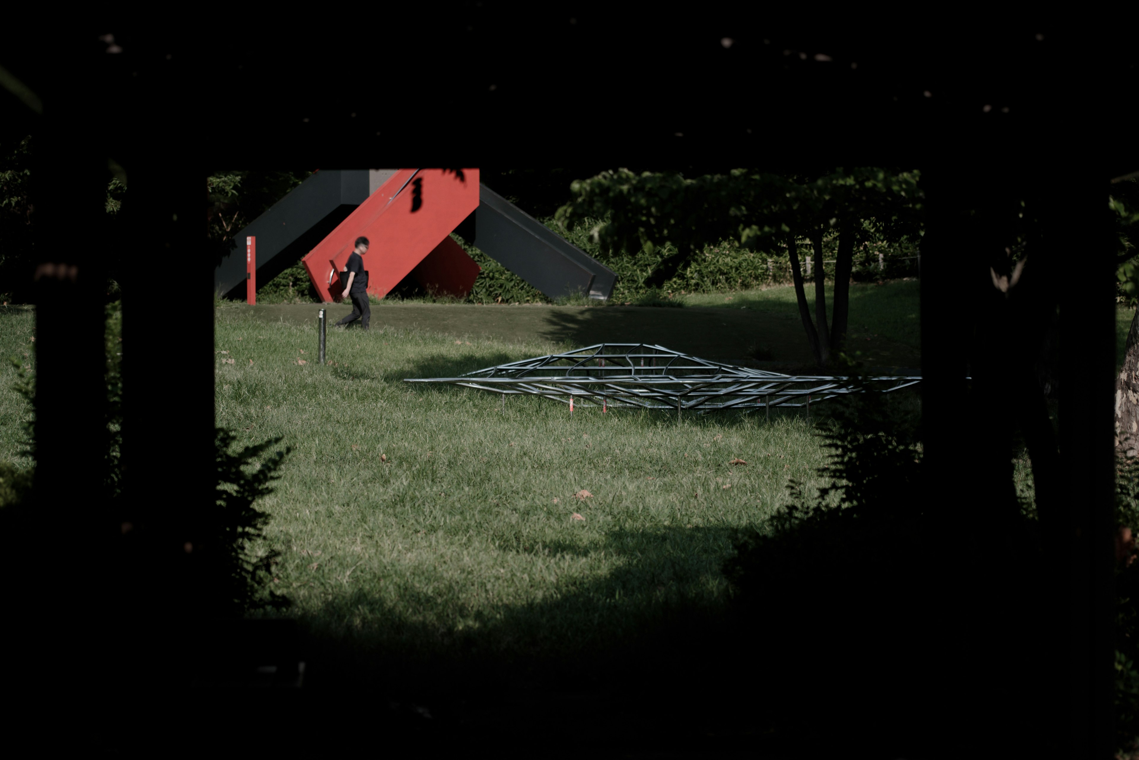 Image d'une personne dans une zone herbeuse avec un bâtiment rouge en arrière-plan