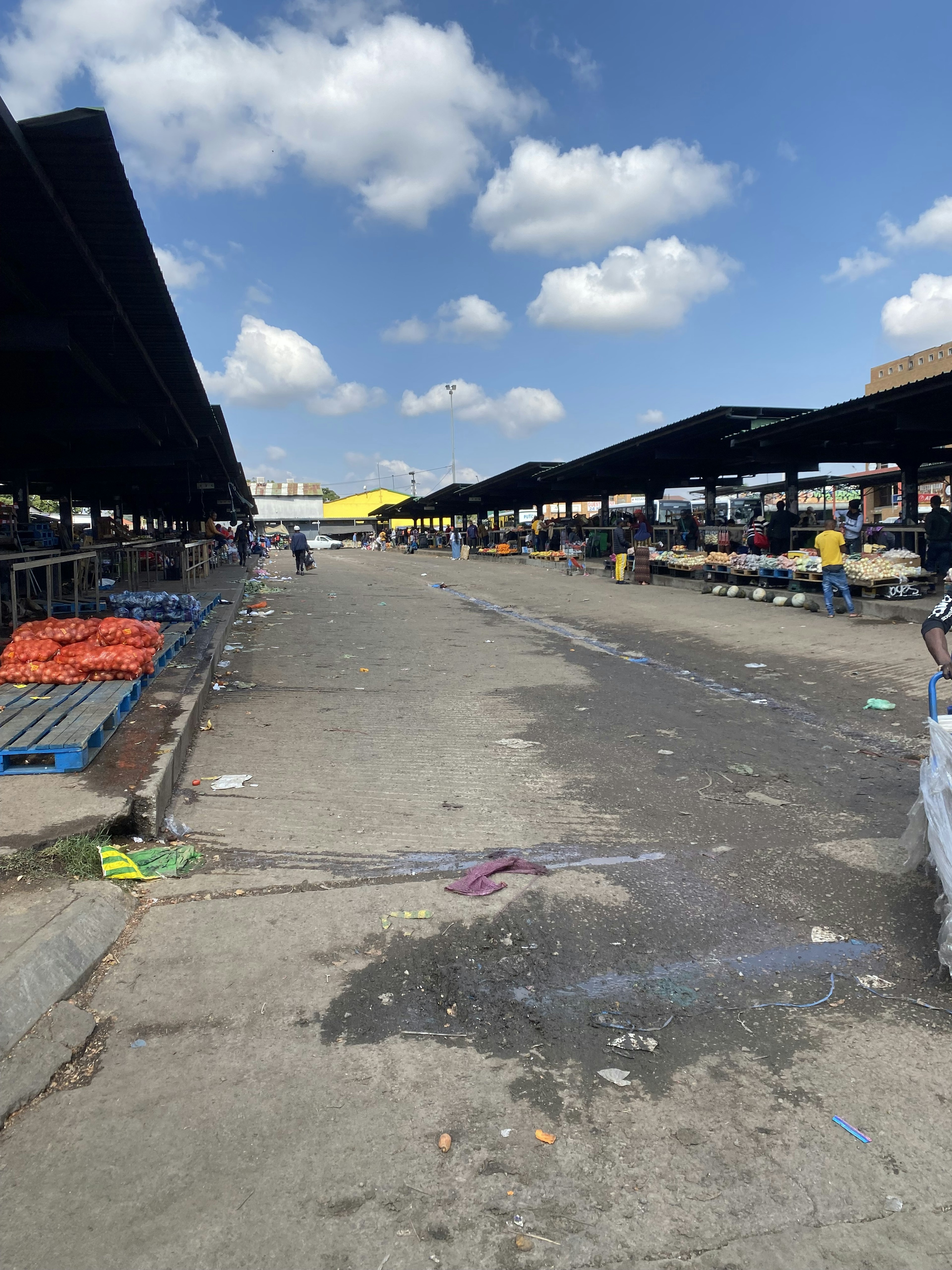 Jalan lebar di pasar luar ruangan di bawah langit biru dengan awan