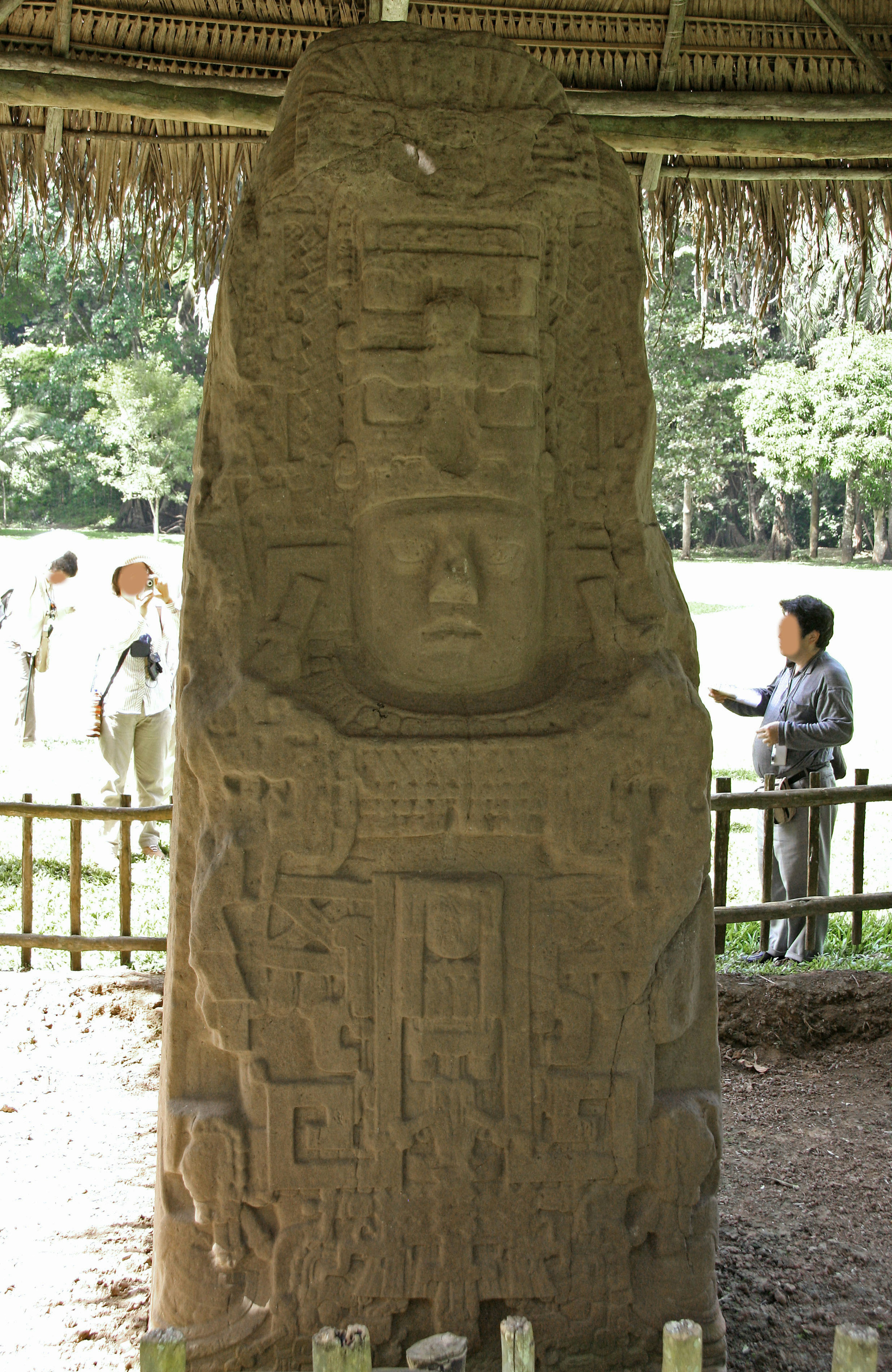 Large ancient stone statue displayed in a landscape featuring carvings of a face and hieroglyphs