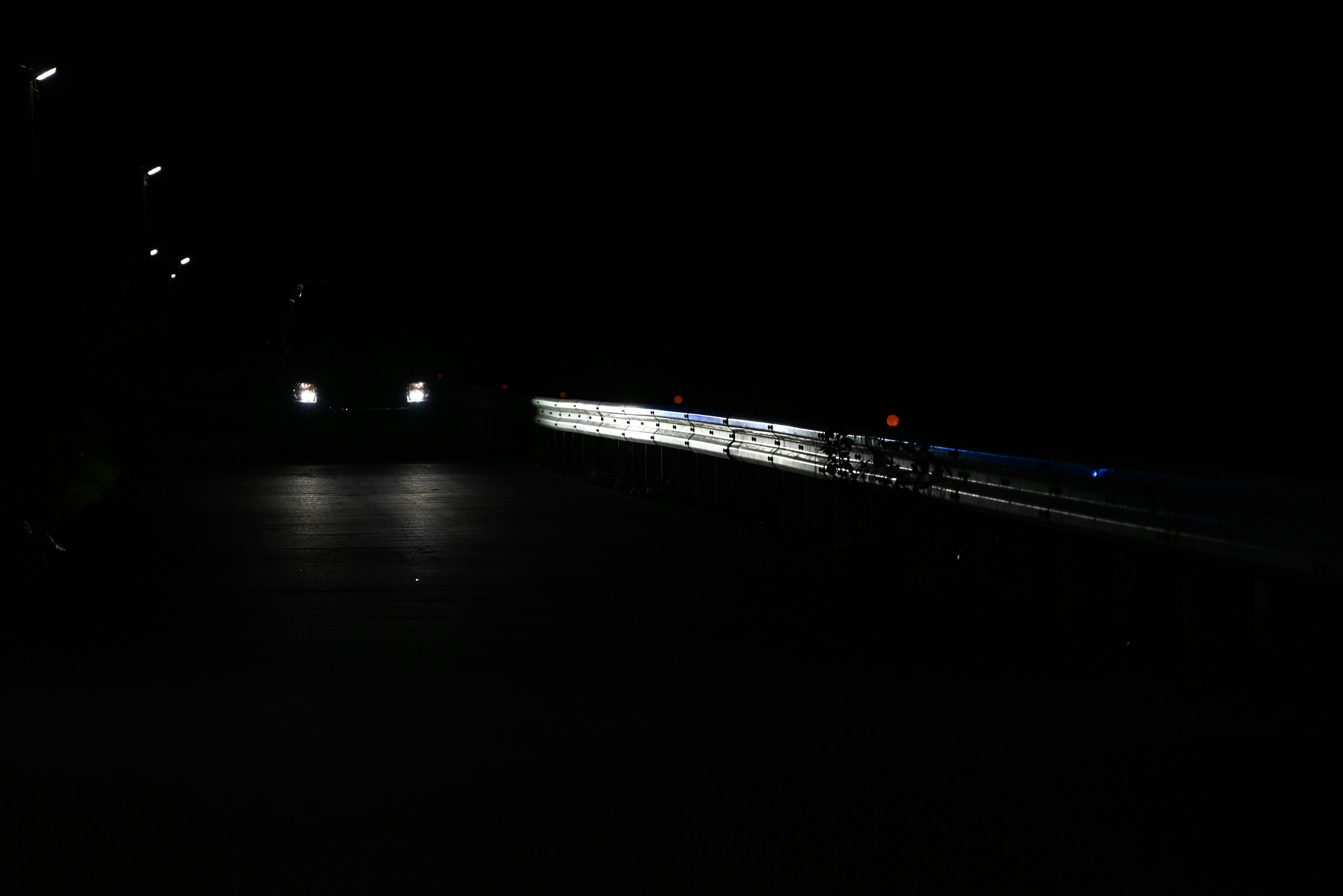 Scene of a dark road illuminated by car headlights