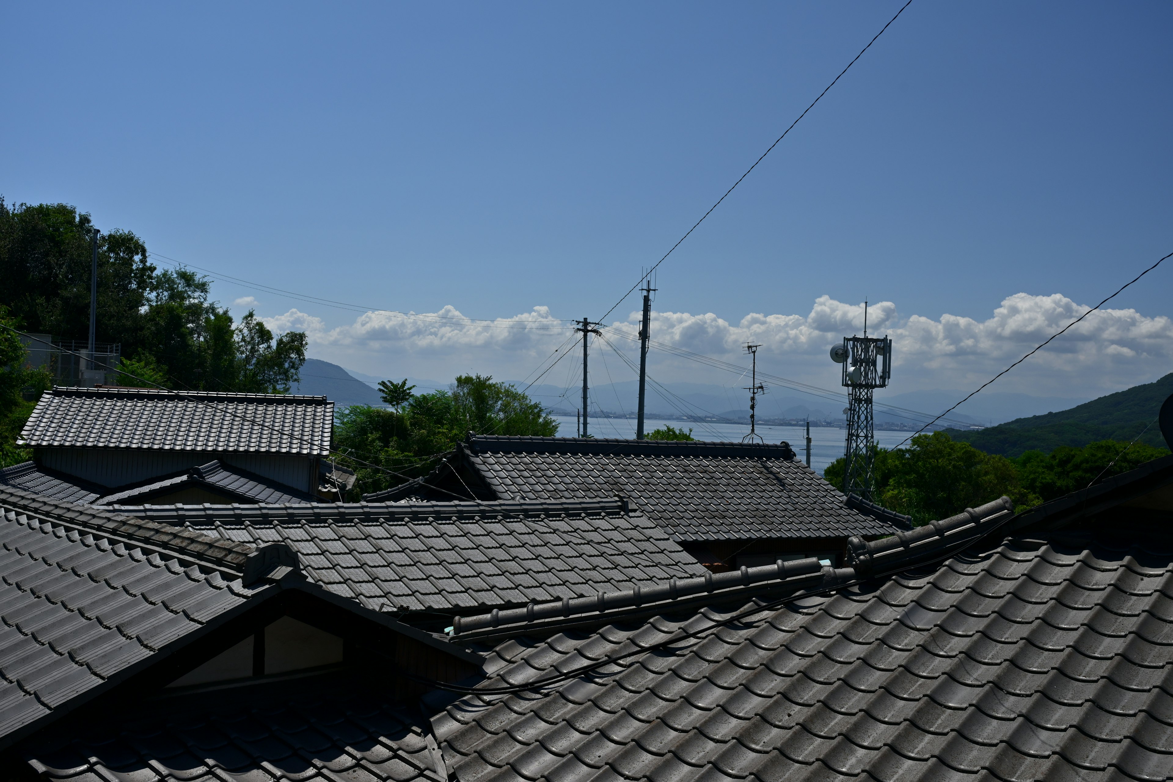 青空の下にある伝統的な日本の家々の屋根と山々の景色