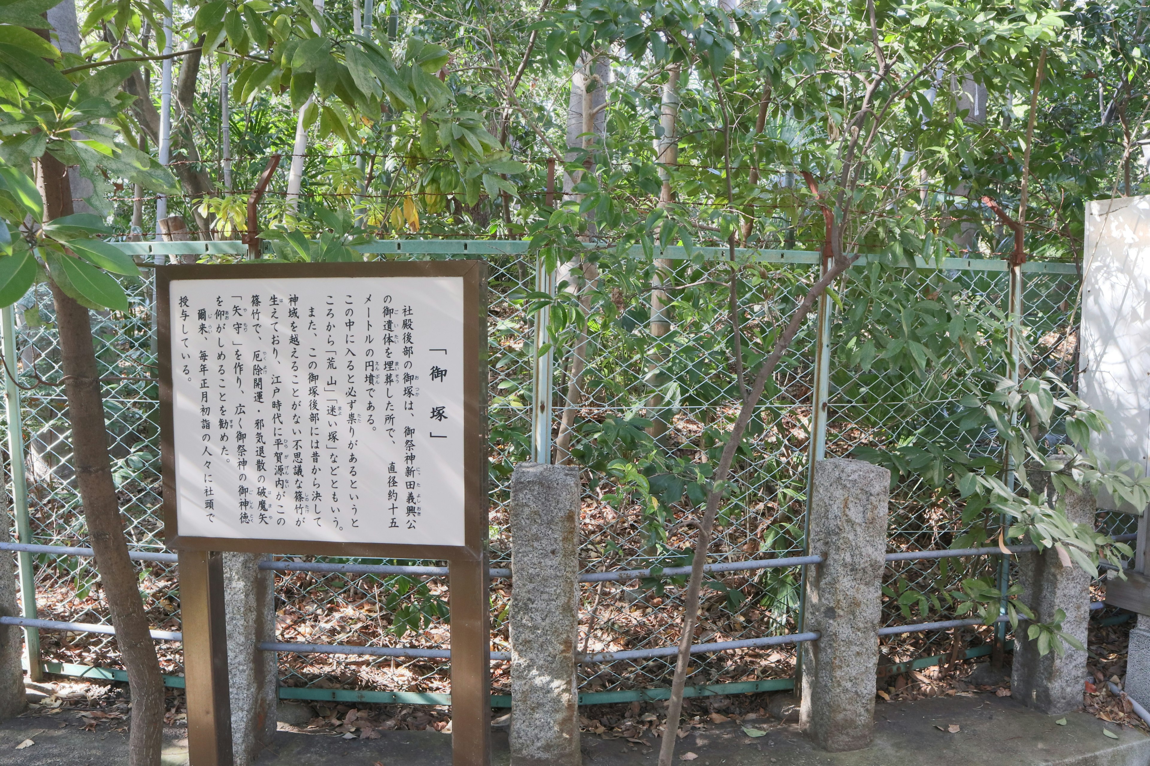 Information board near a green, lush fenced area