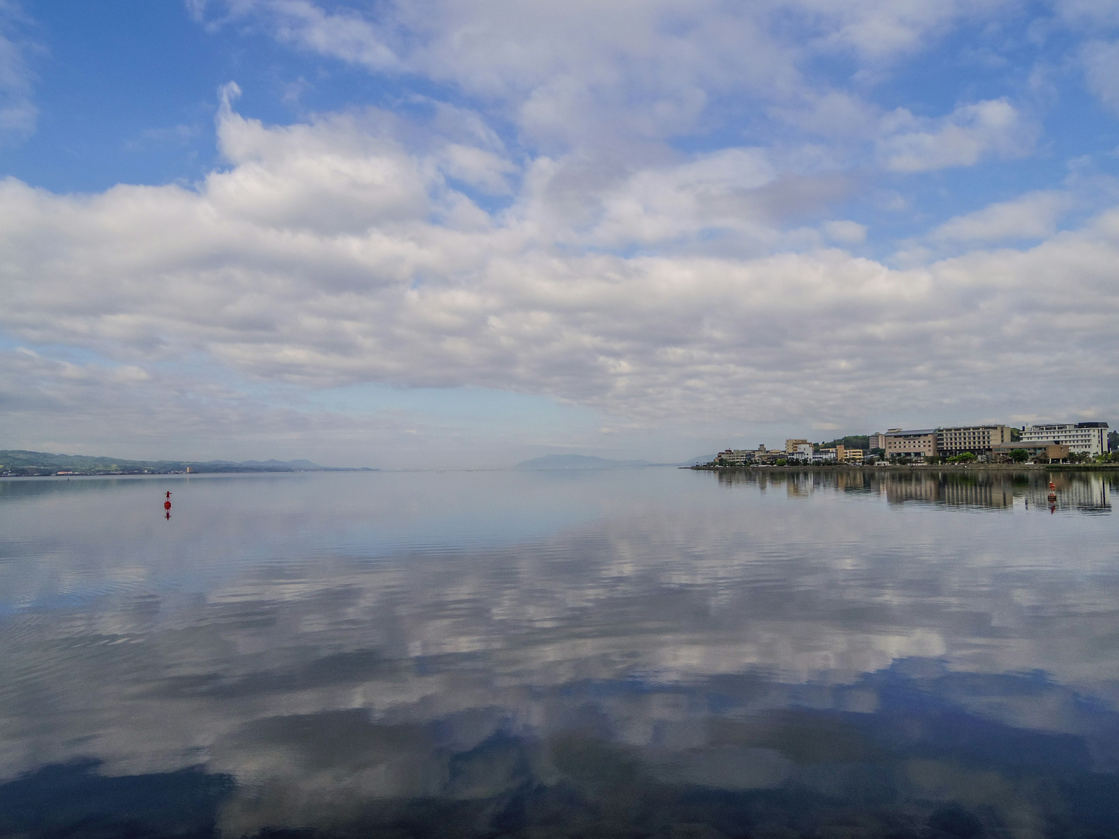 Serene lake reflecting clouds and buildings