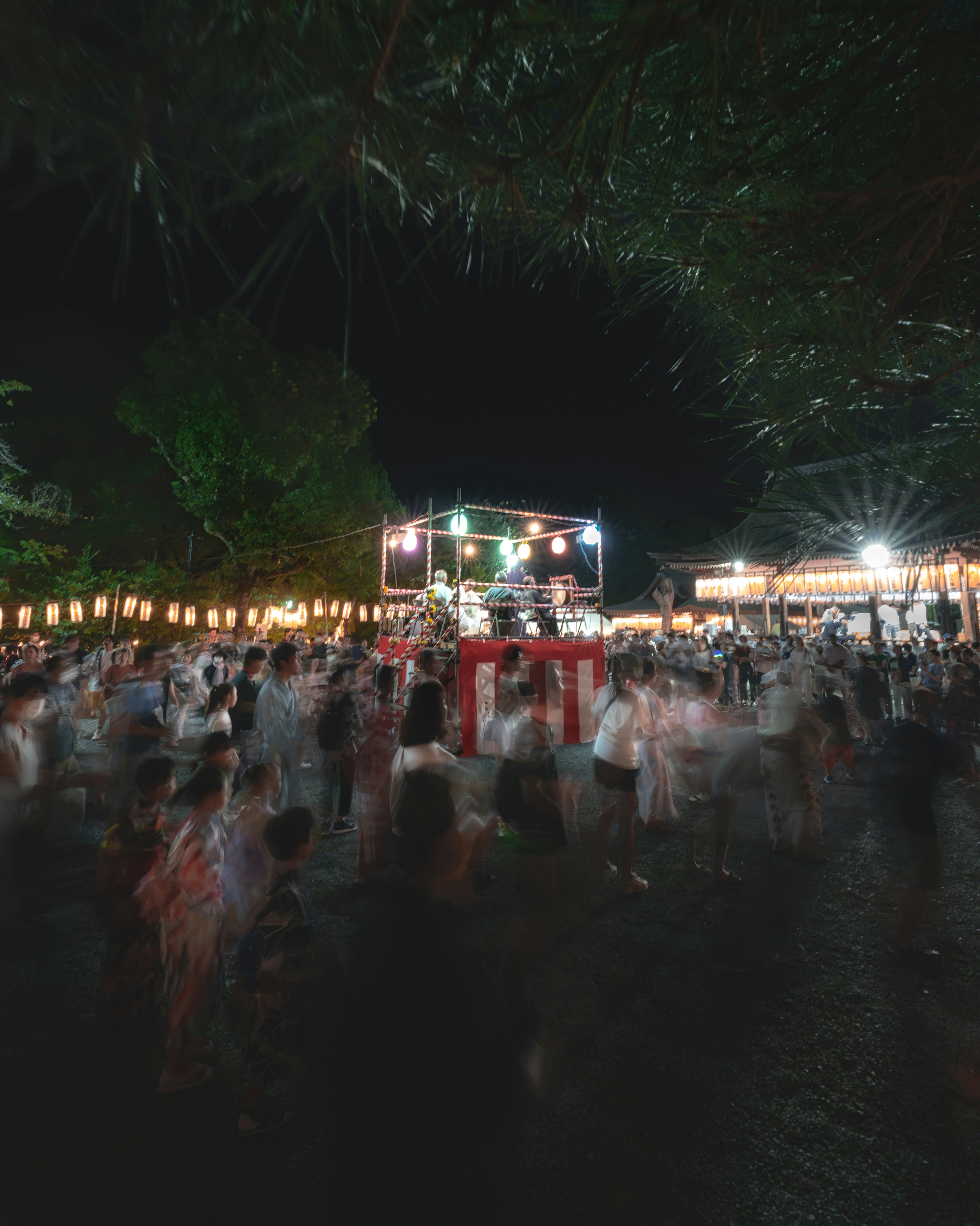 Événement nocturne en plein air avec de nombreuses personnes dansant DJ sur scène et lumières vives environnantes