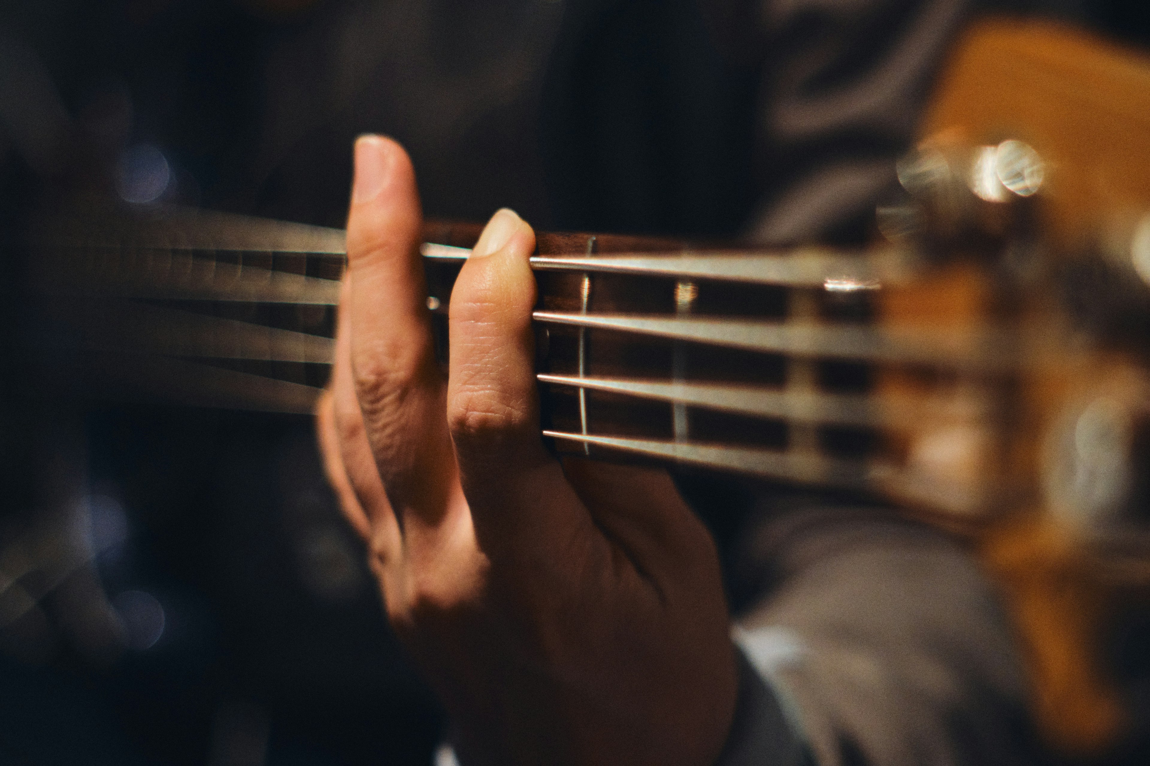 Close-up of a hand pressing the strings of a bass guitar