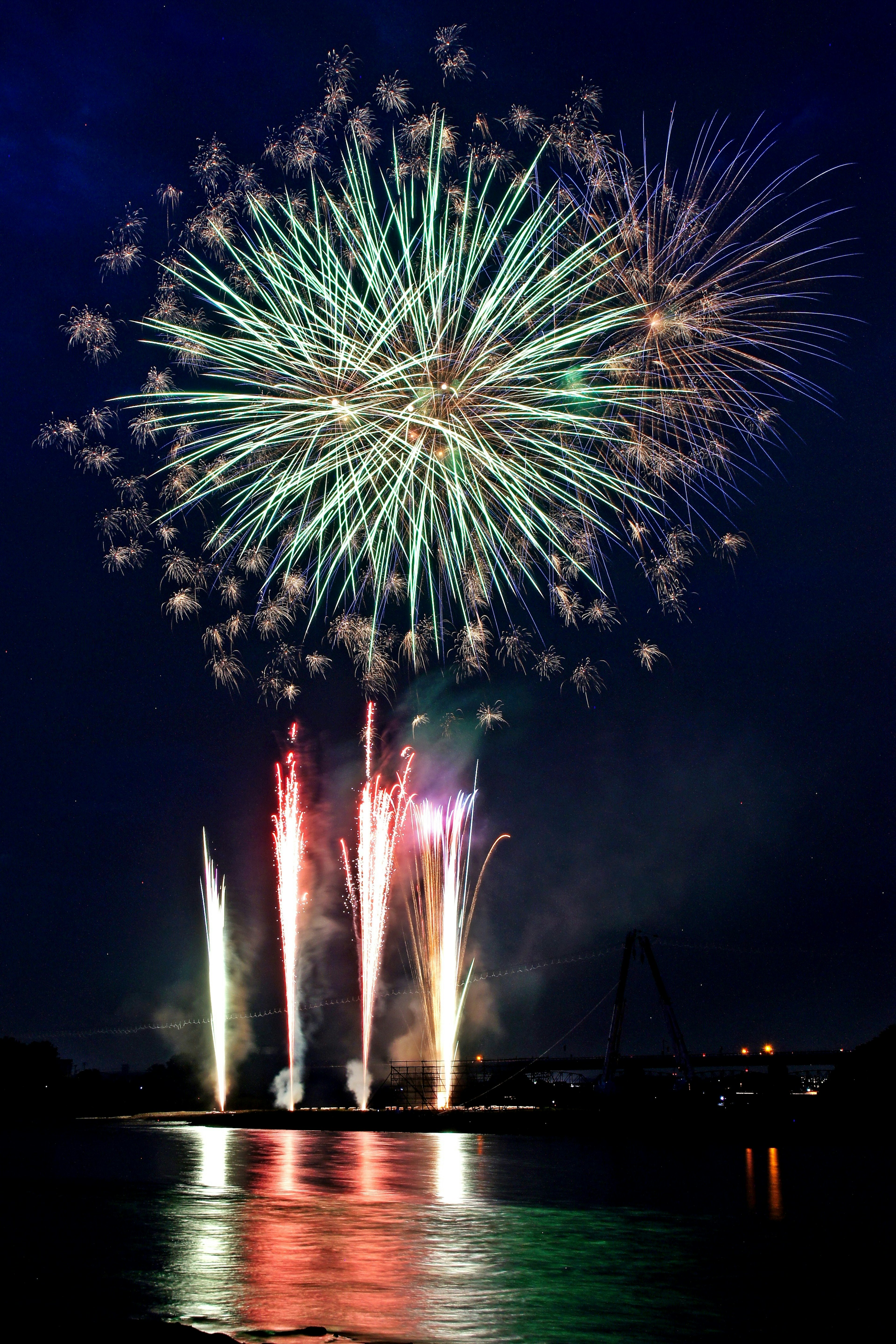 Magnifique spectacle de feux d'artifice dans le ciel nocturne avec des couleurs vives se reflétant sur l'eau