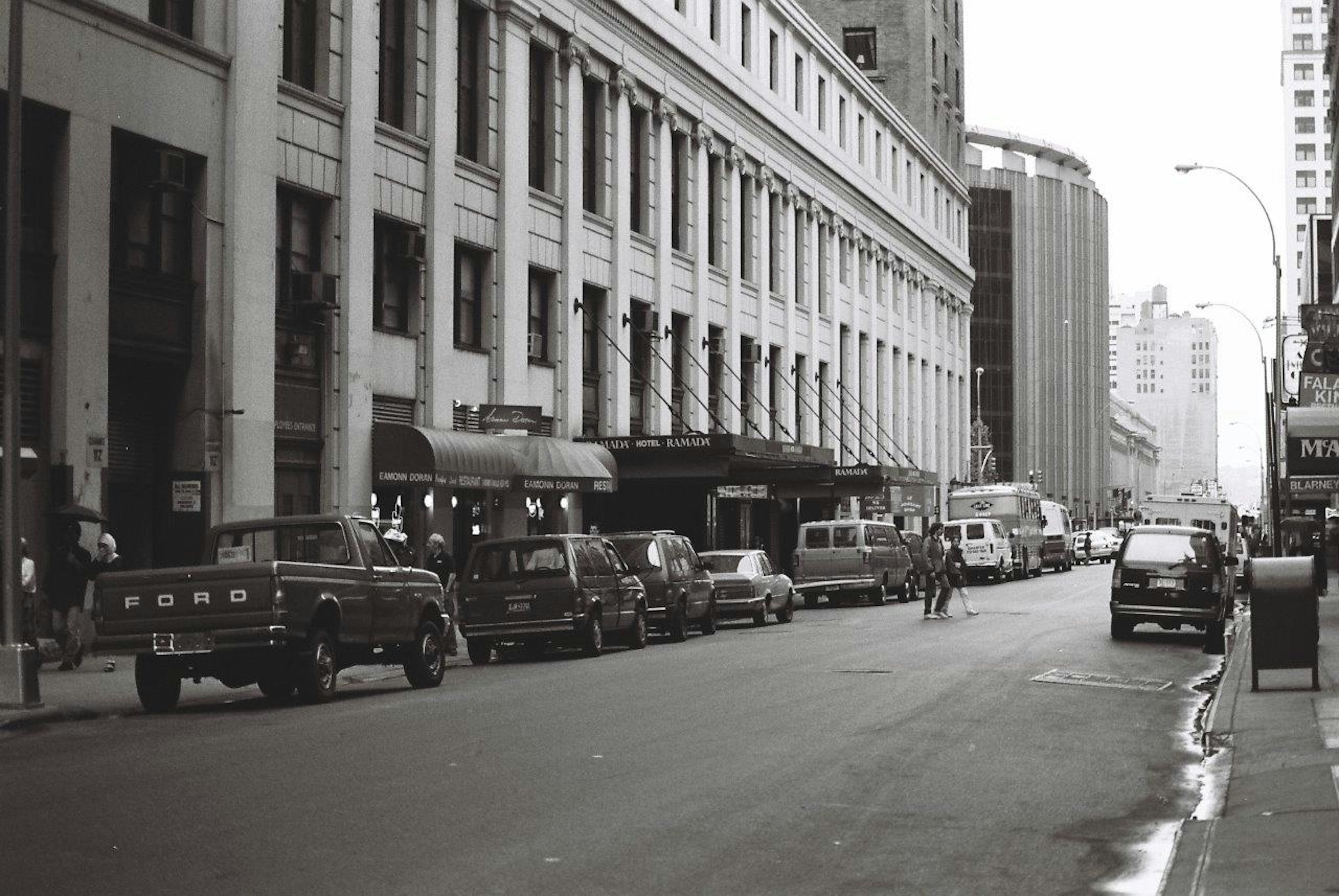 Vue de rue en noir et blanc avec de vieux bâtiments et divers véhicules alignés