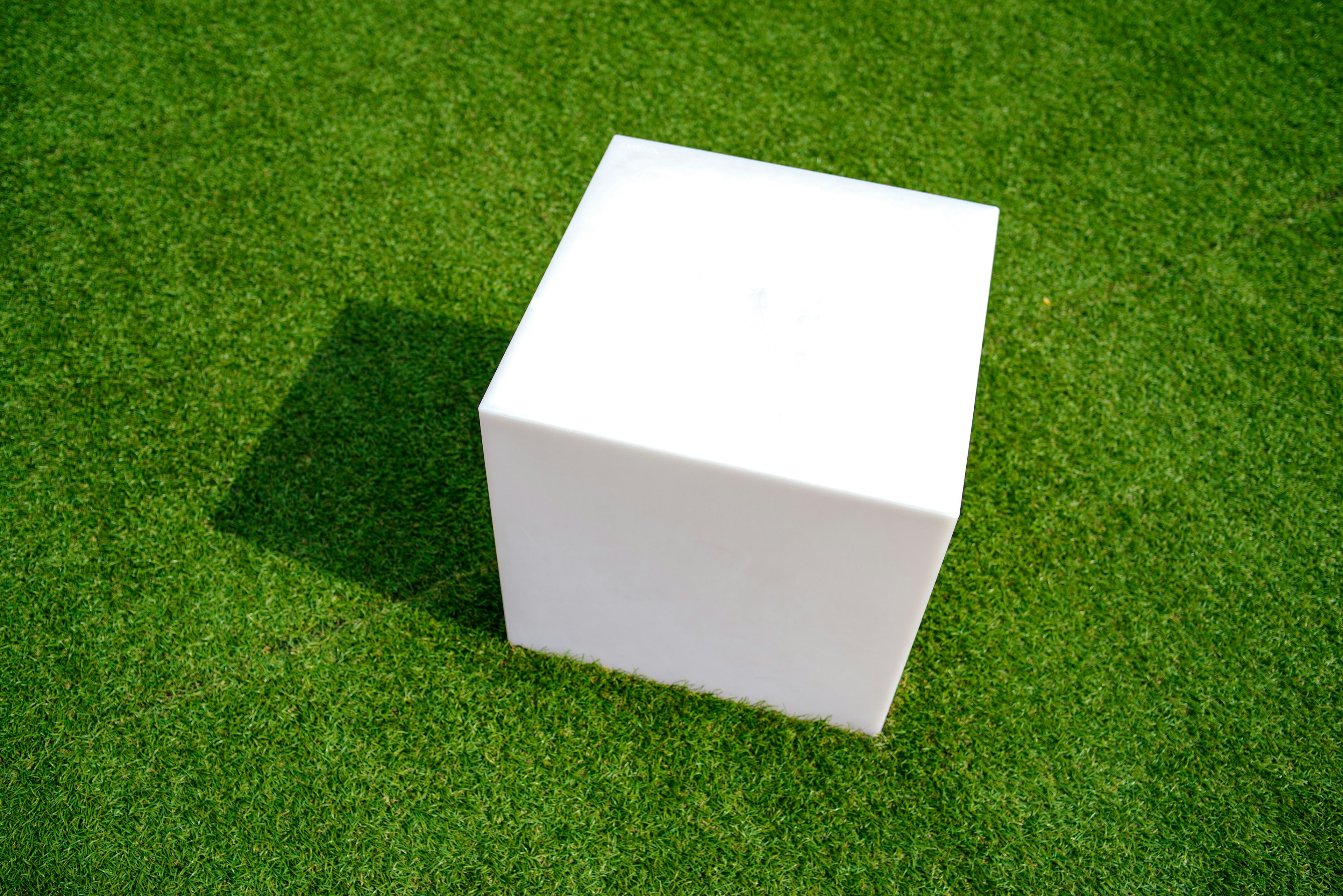 Cubo blanco colocado sobre hierba verde