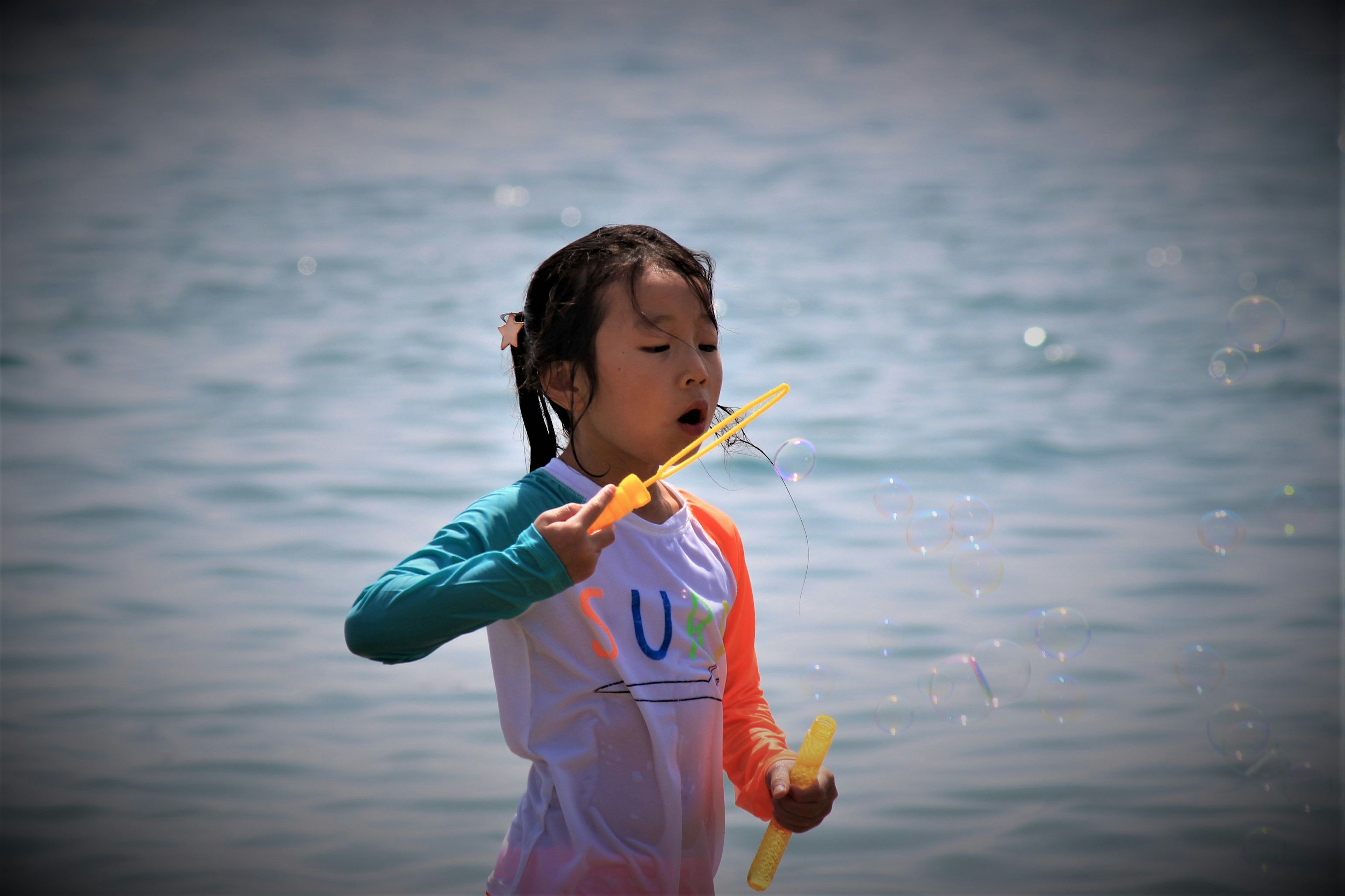 Child blowing bubbles at the water's edge