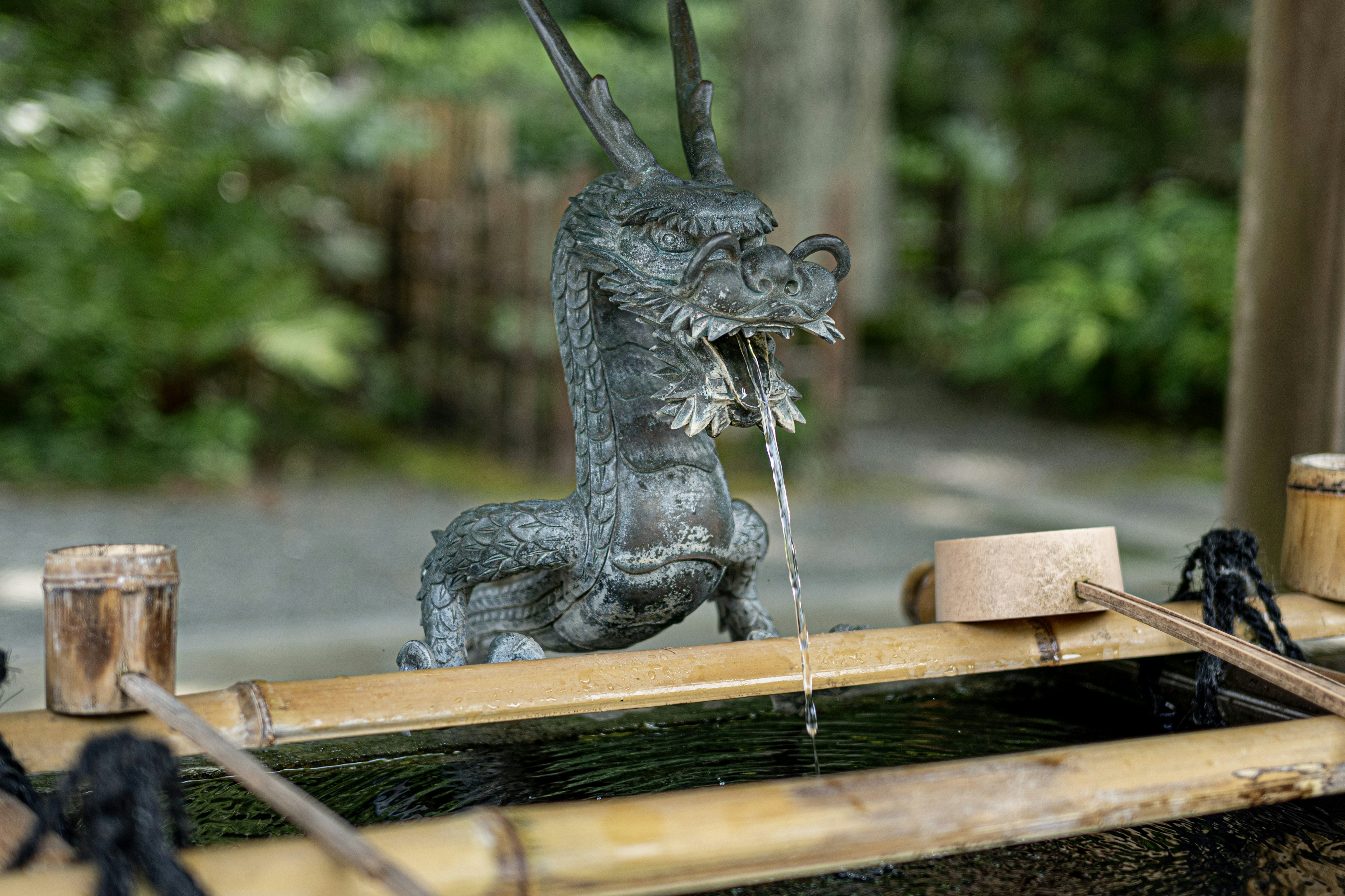 Statue de dragon en bronze versant de l'eau dans un bassin en bambou