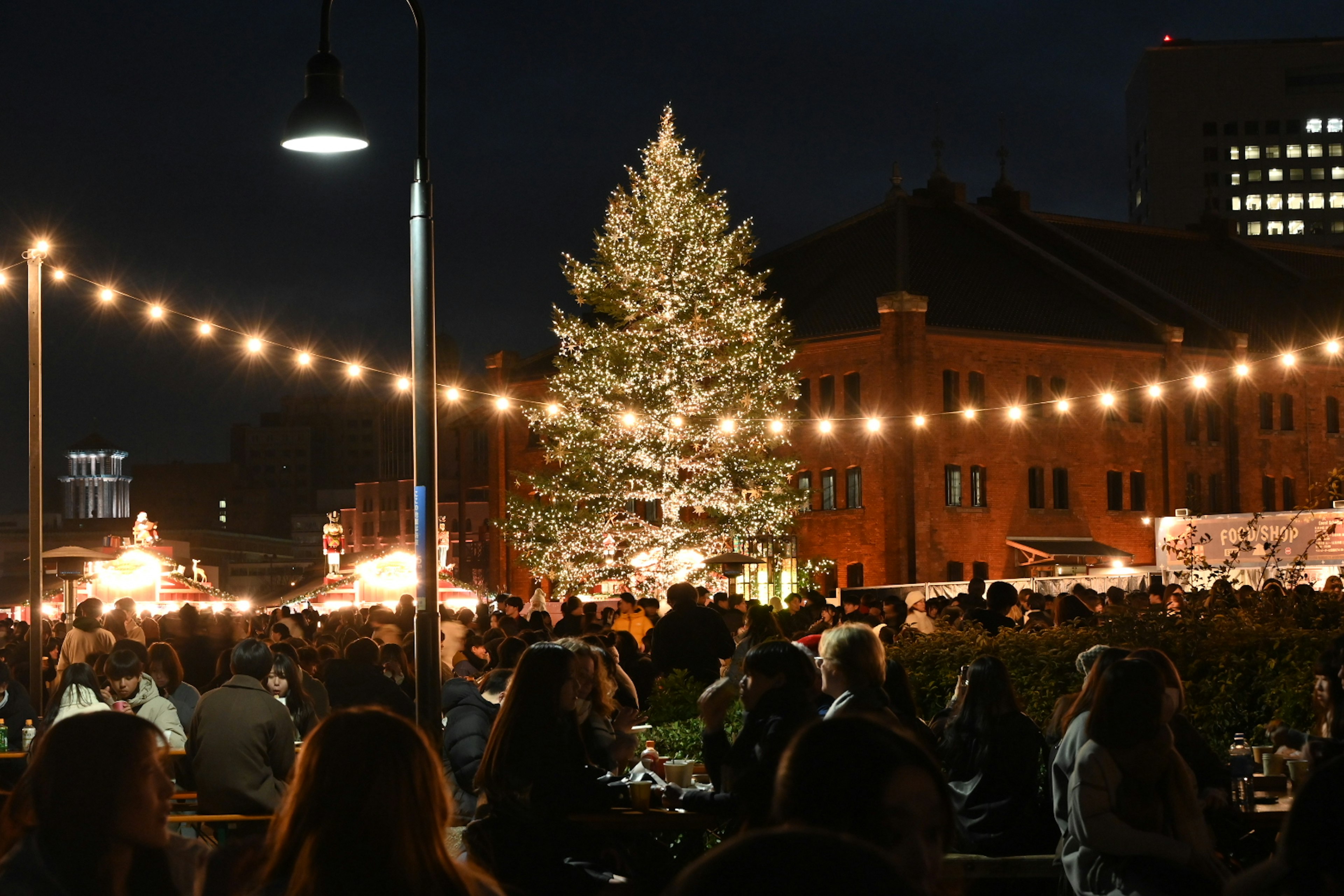 Bustling Christmas market at night with a glowing Christmas tree