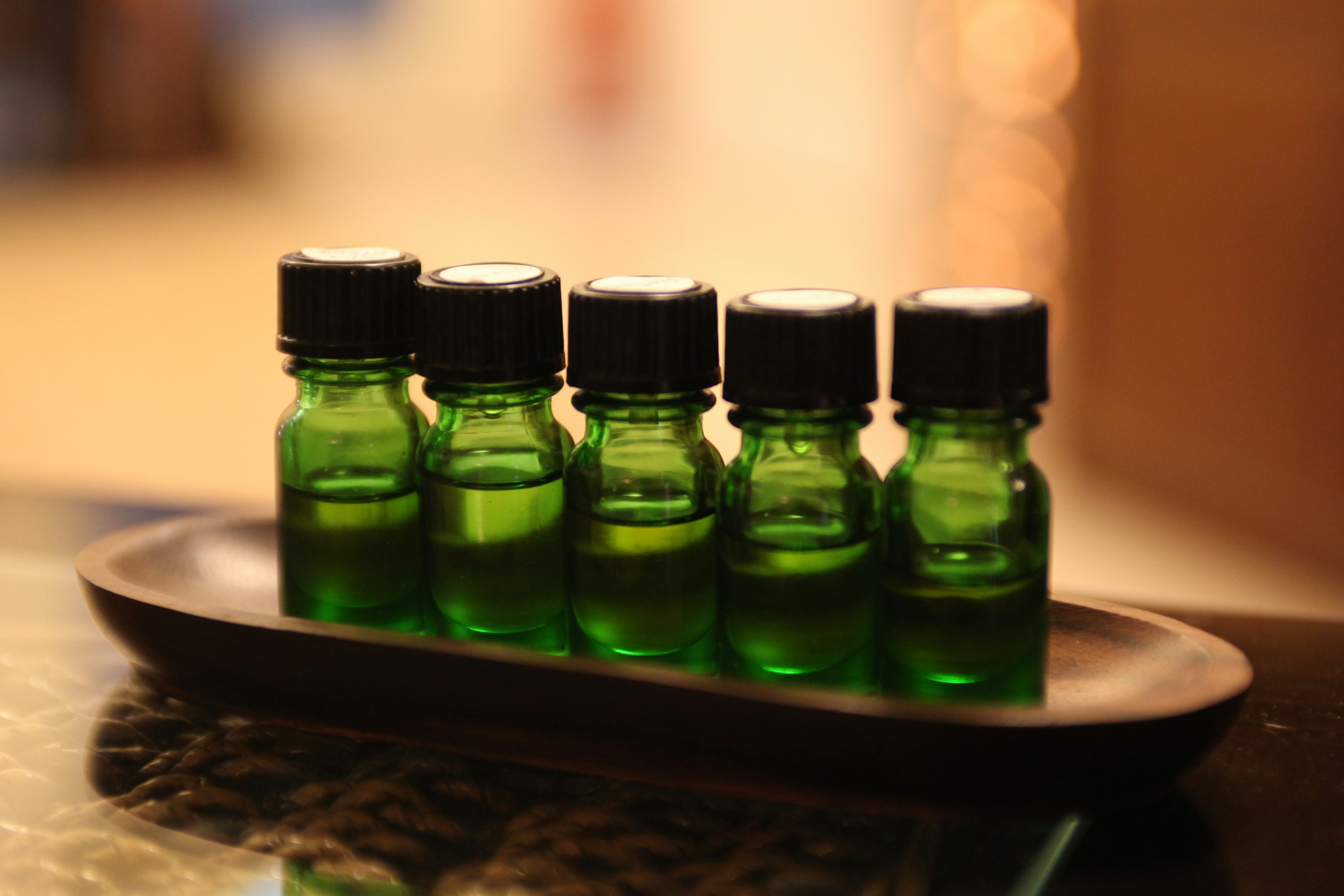 Five green bottles lined up on a tray with black caps