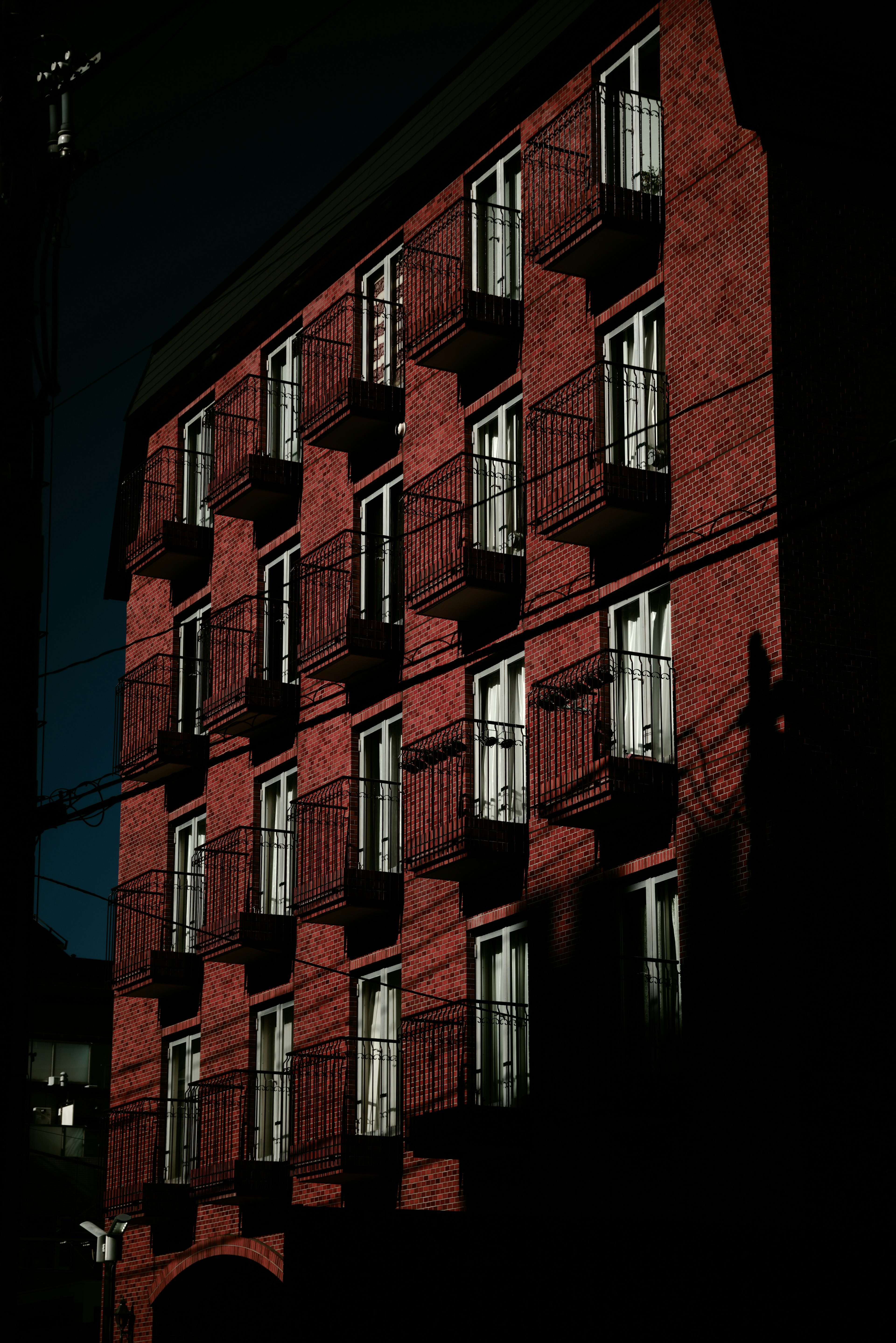 Vista nocturna de un edificio rojo con ventanas de balcón