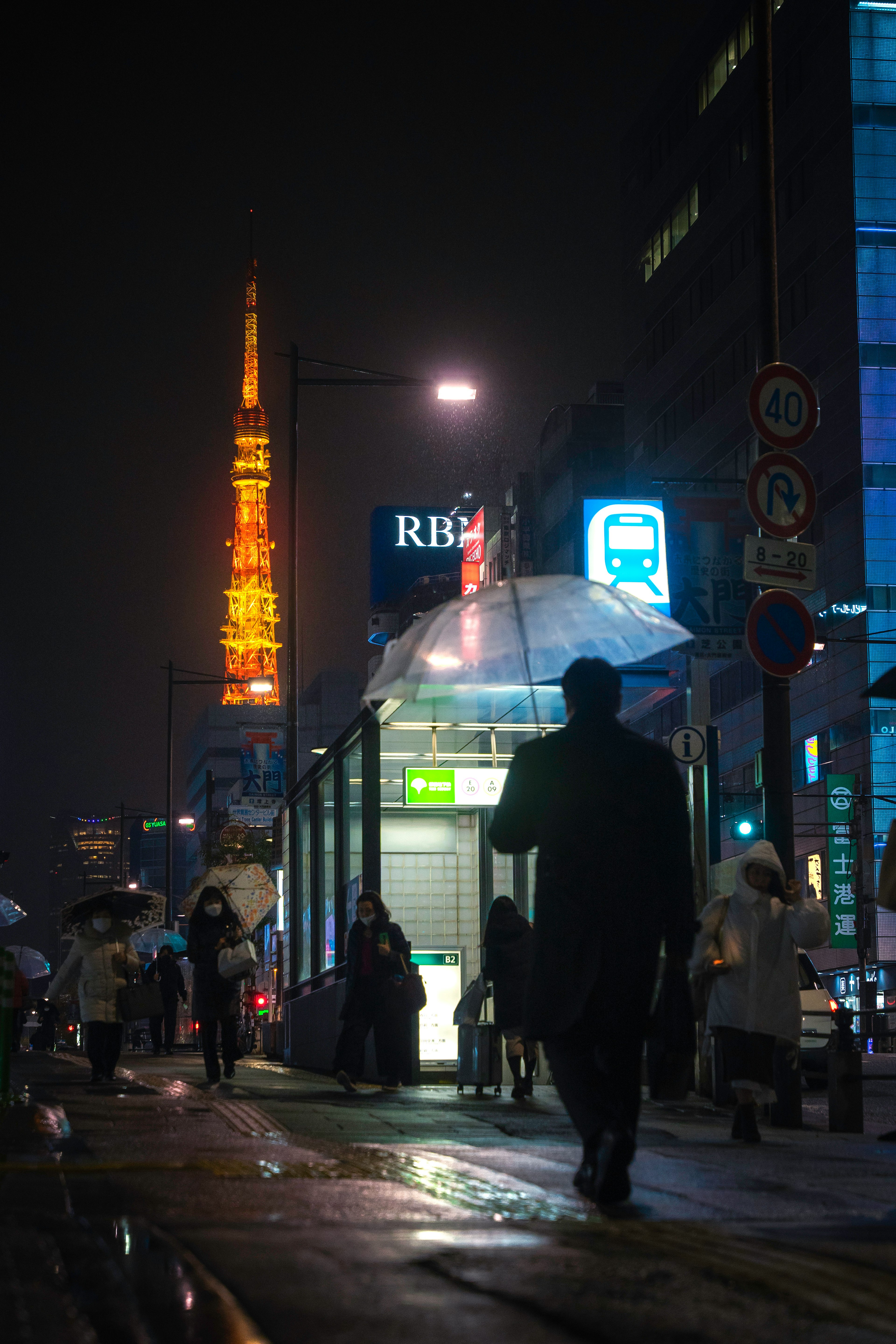 夜の街で傘を持って歩く人影と東京タワーの明かり