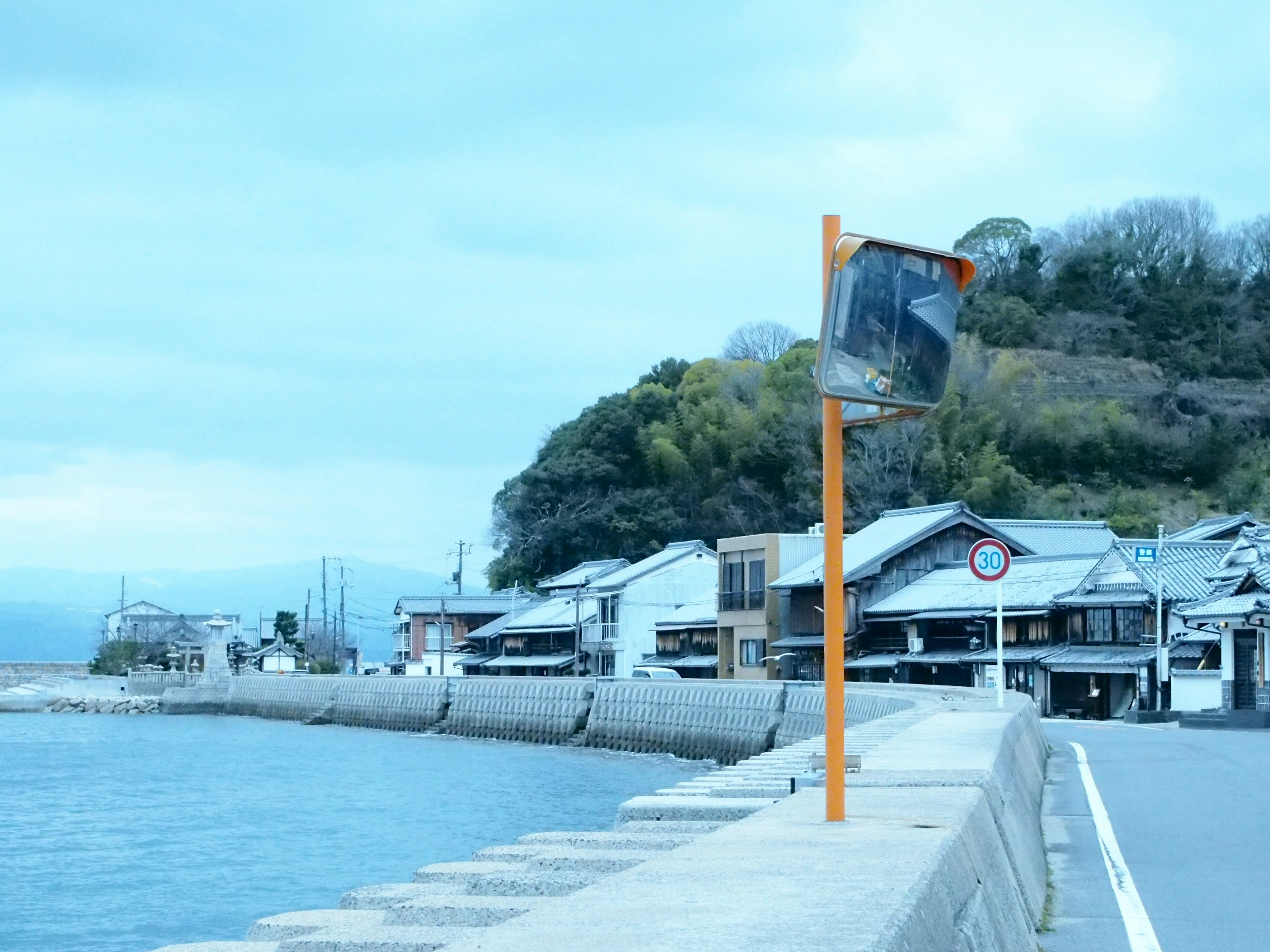 静かな港町の風景、青い海と曇り空、オレンジ色の標識と伝統的な建物