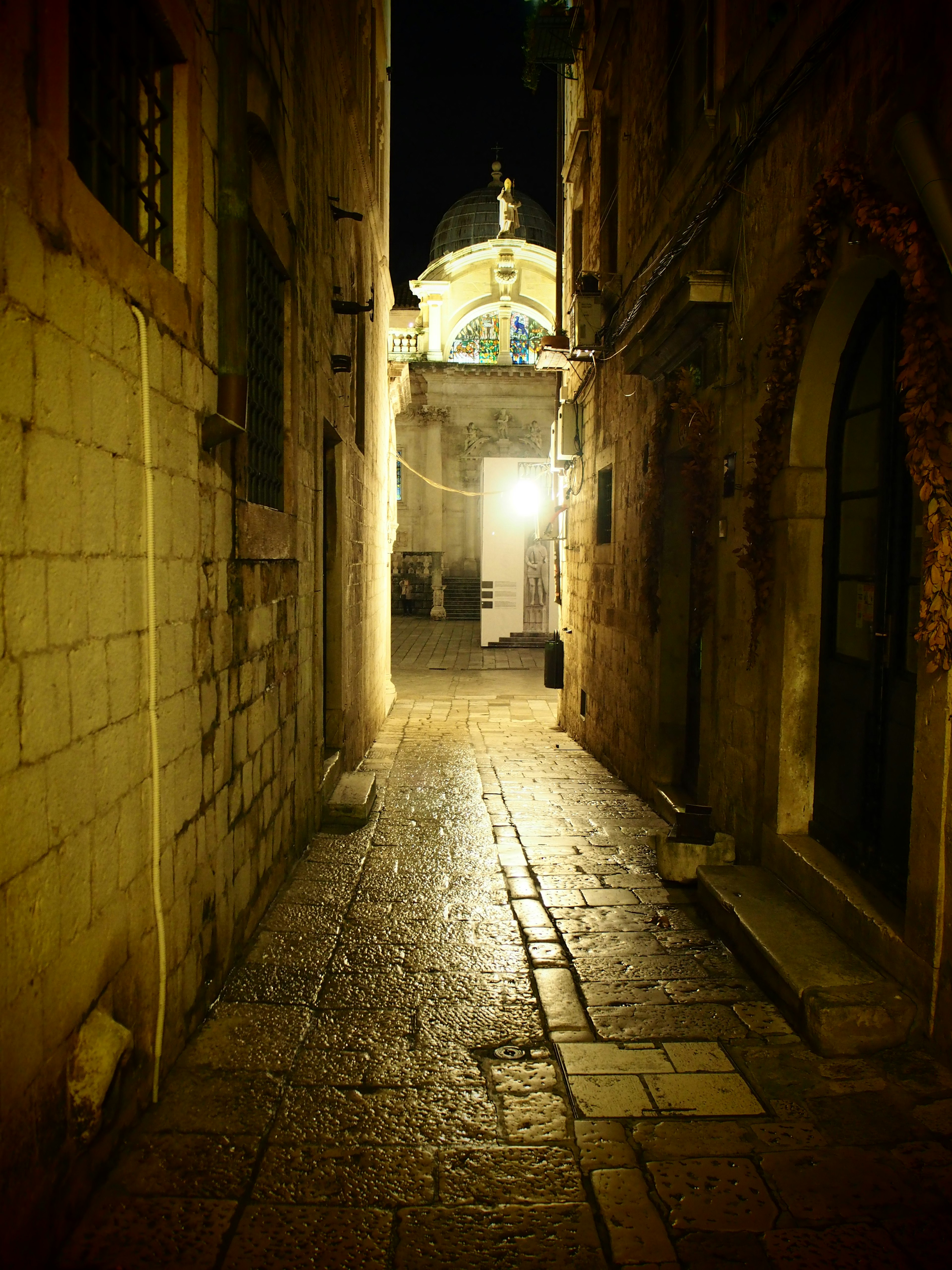 Narrow stone alley at night with illuminated building