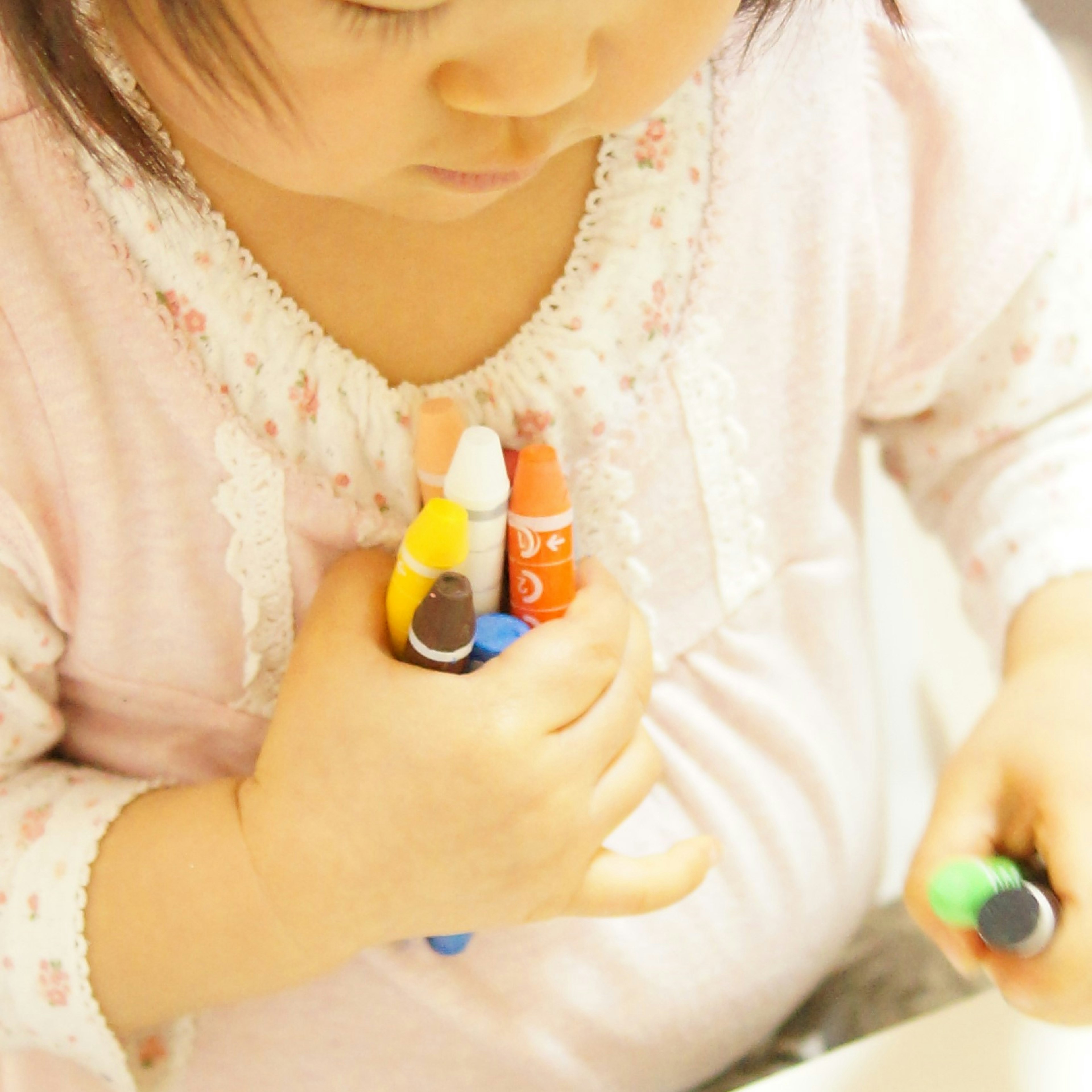 A young girl holding colorful crayons