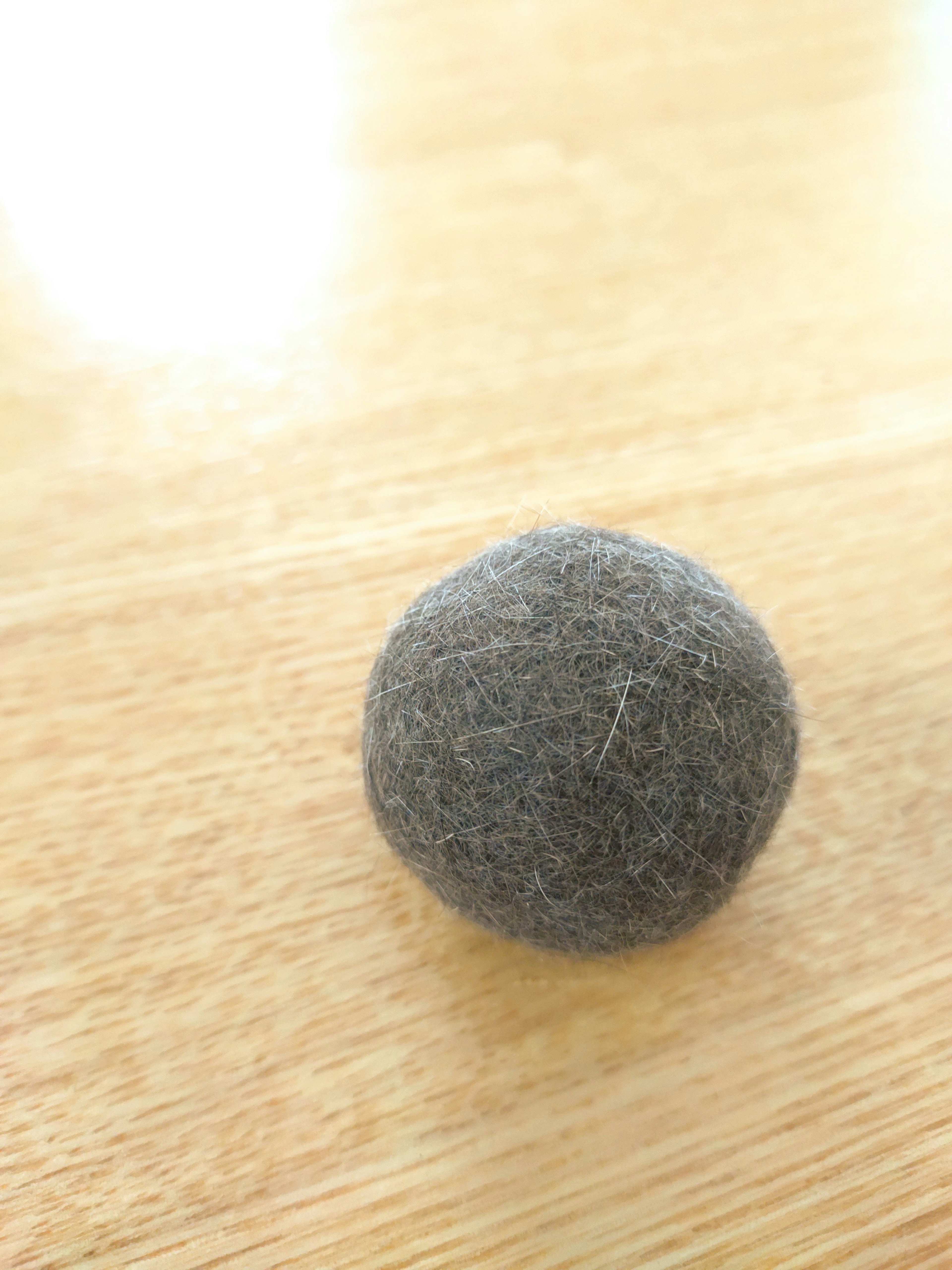 Boule en feutre grise reposant sur une table en bois