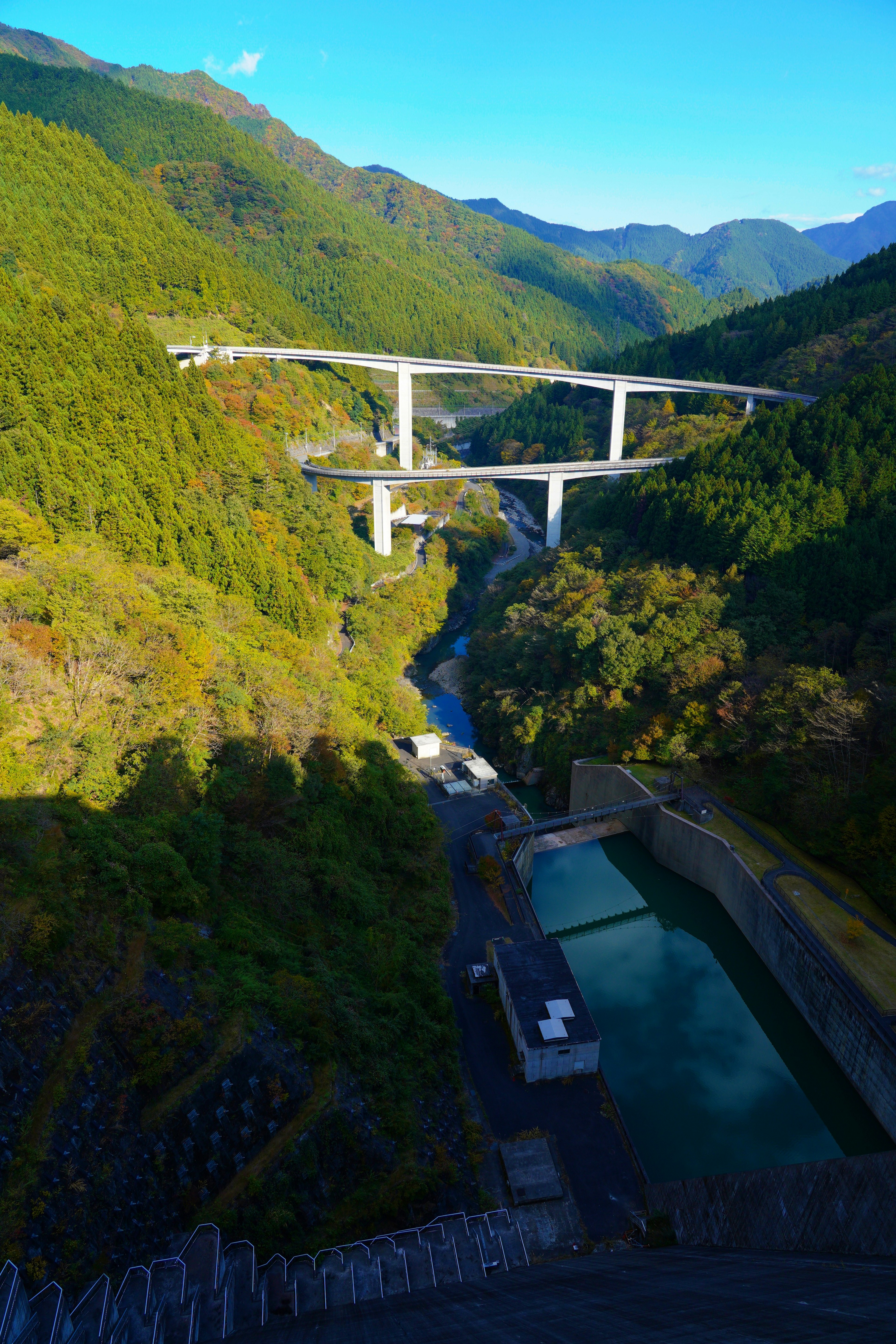 Une vue pittoresque d'un pont surélevé surplombant une rivière entourée de montagnes verdoyantes