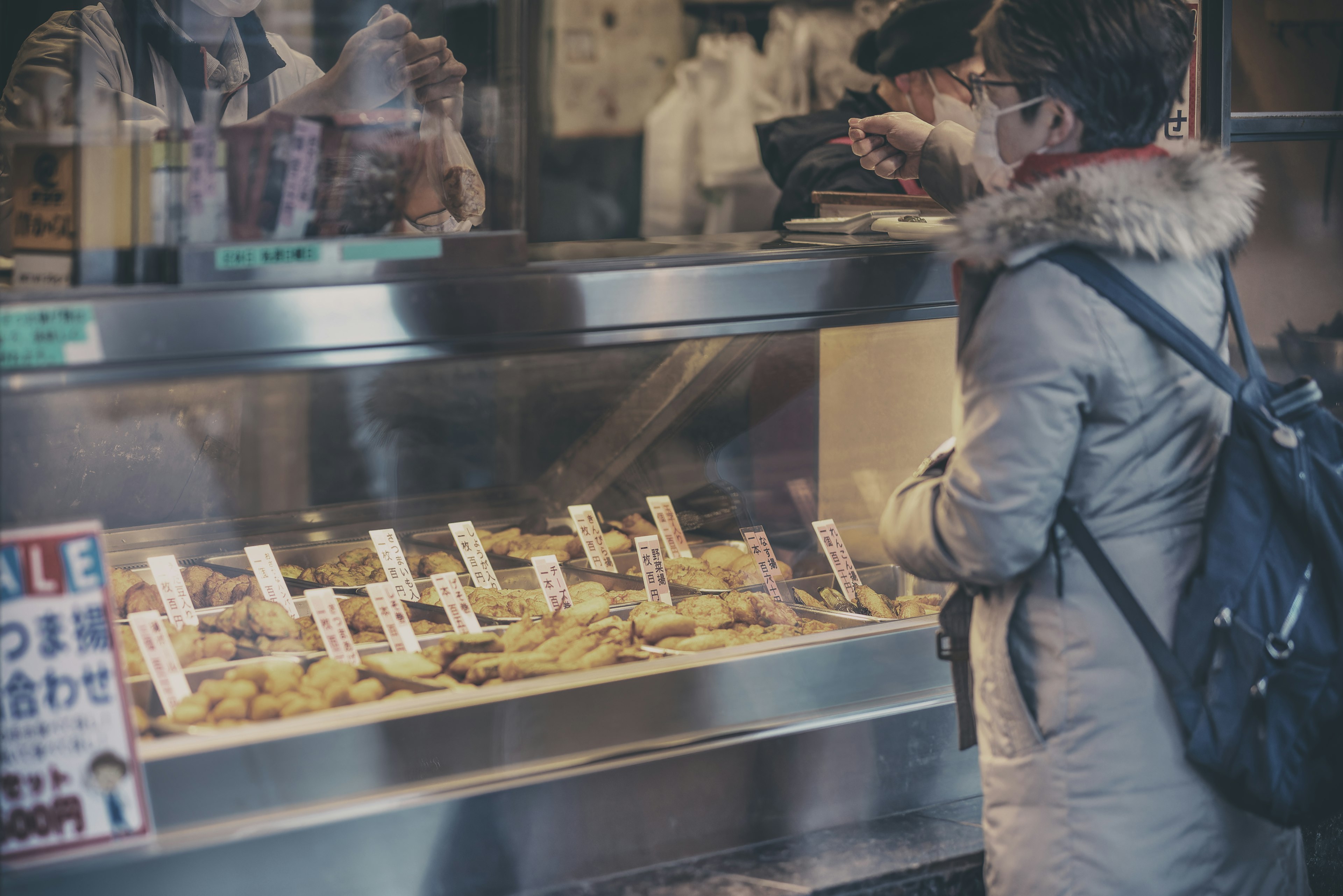 Una persona de pie frente a un puesto de comida eligiendo artículos