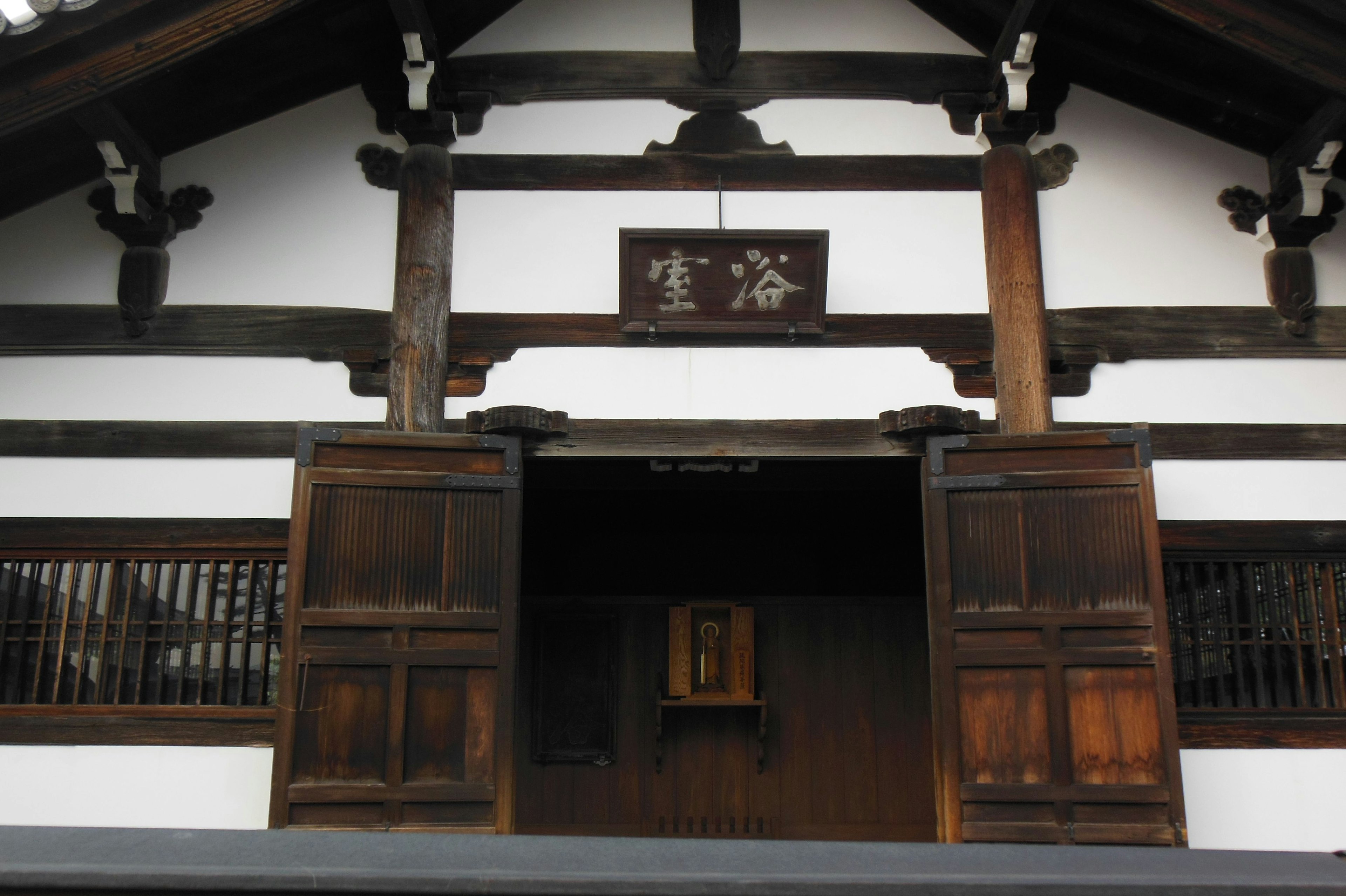 Traditional Japanese building entrance featuring wooden doors and white walls