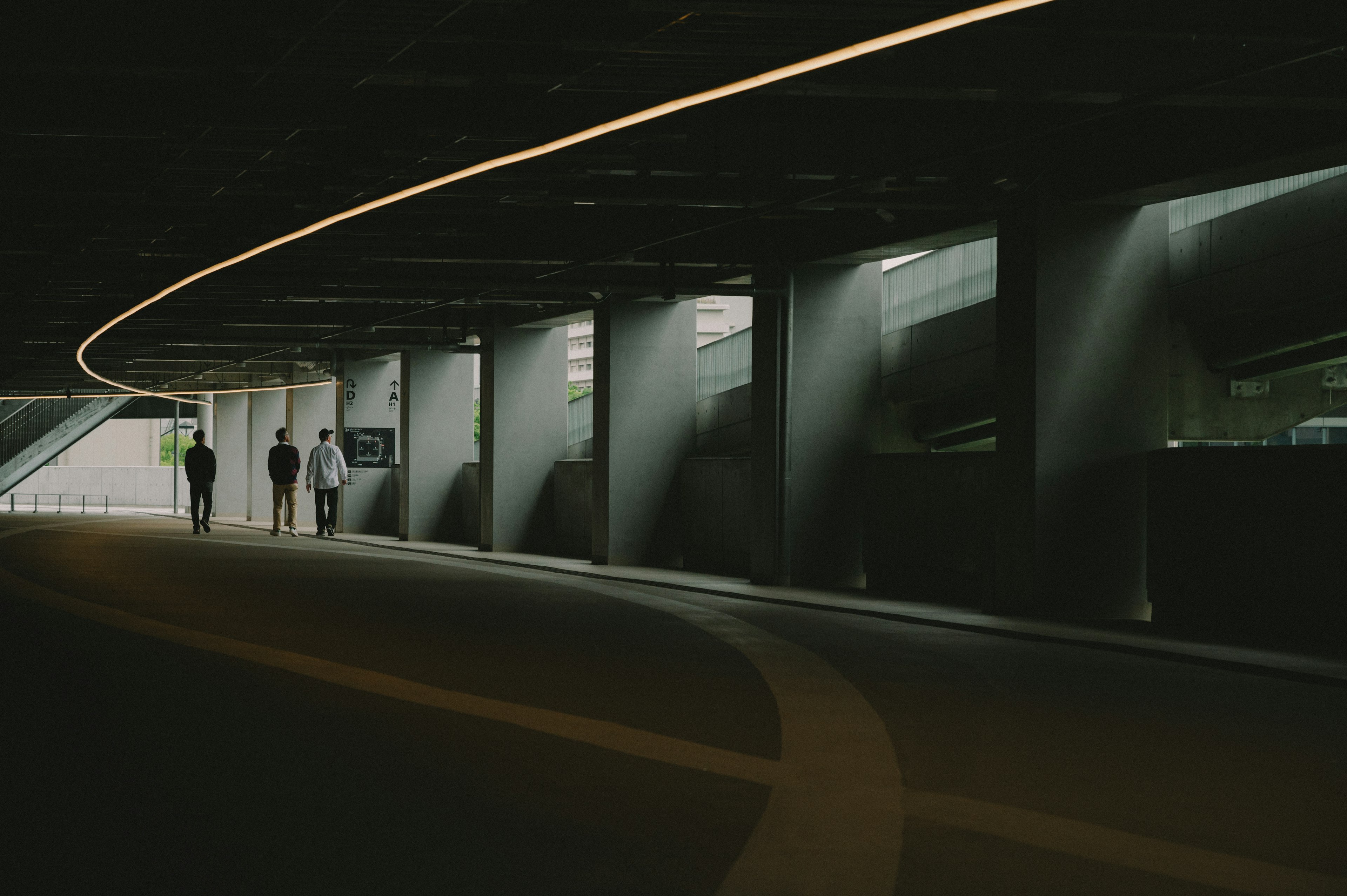 Menschen gehen in einem dunklen Tunnel mit sanfter, geschwungener Beleuchtung