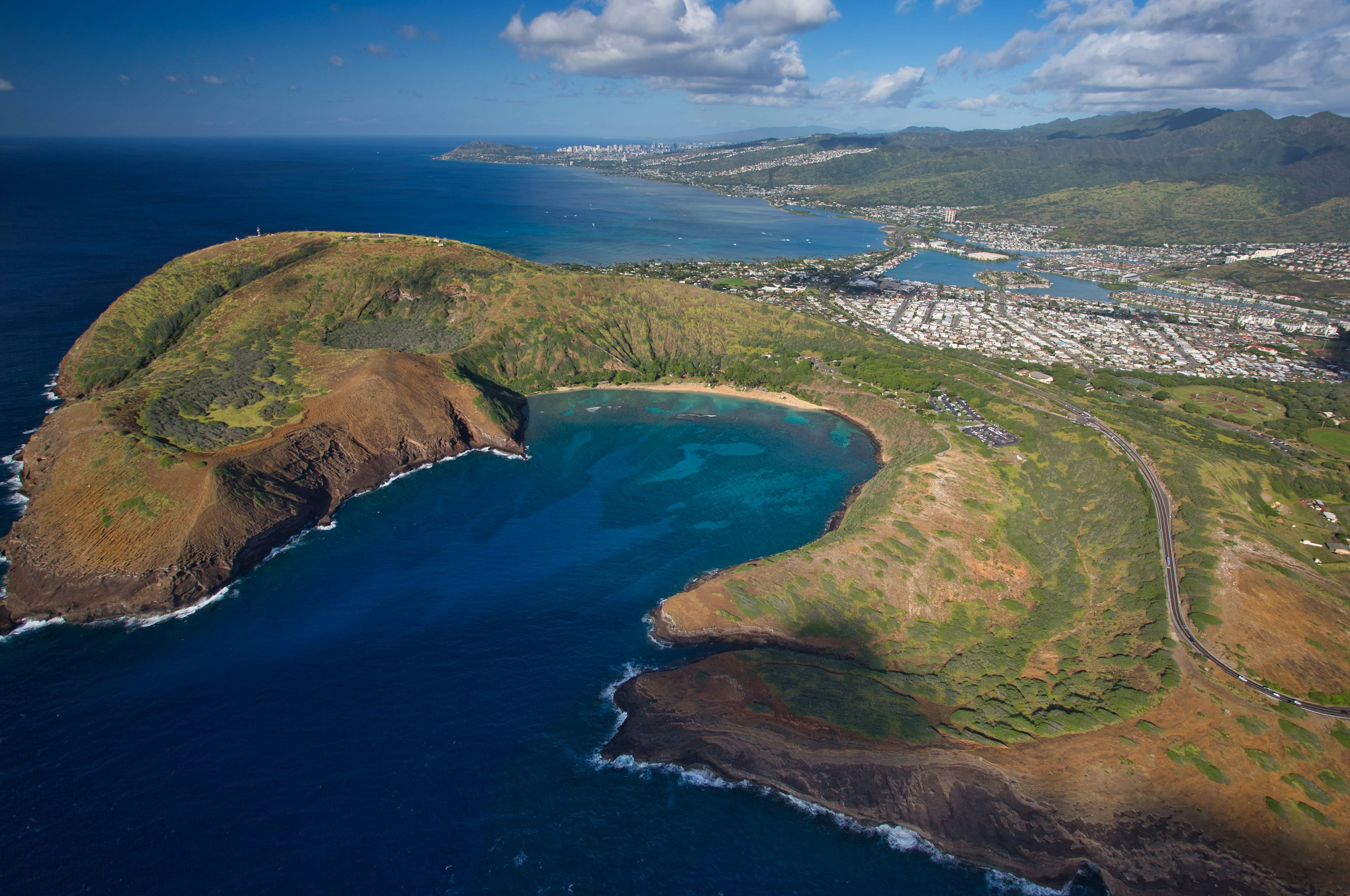 Luftaufnahme der Küste von Hawaii mit grünen Hügeln und blauem Wasser