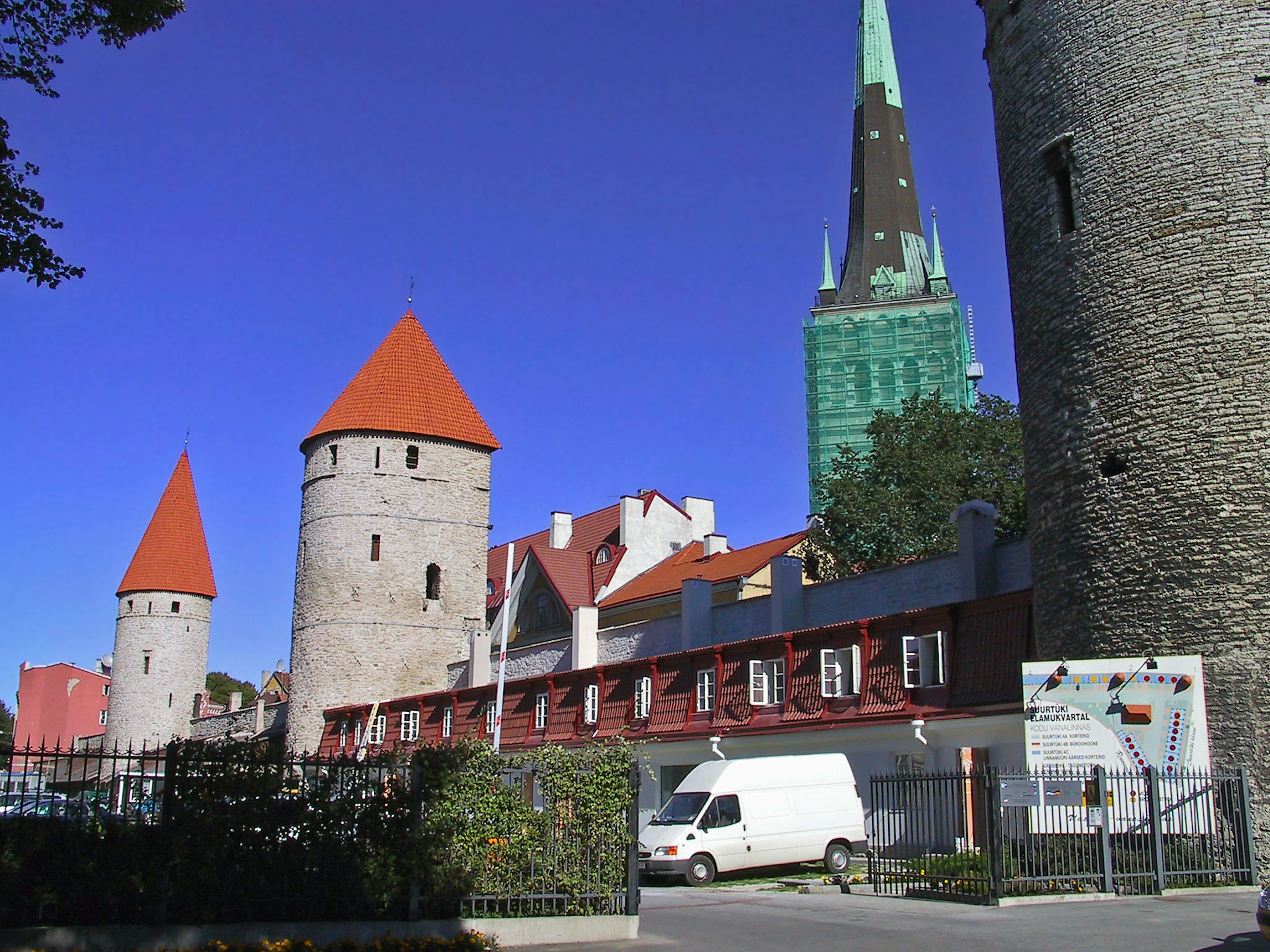 View of medieval towers with red roofs and a green spire