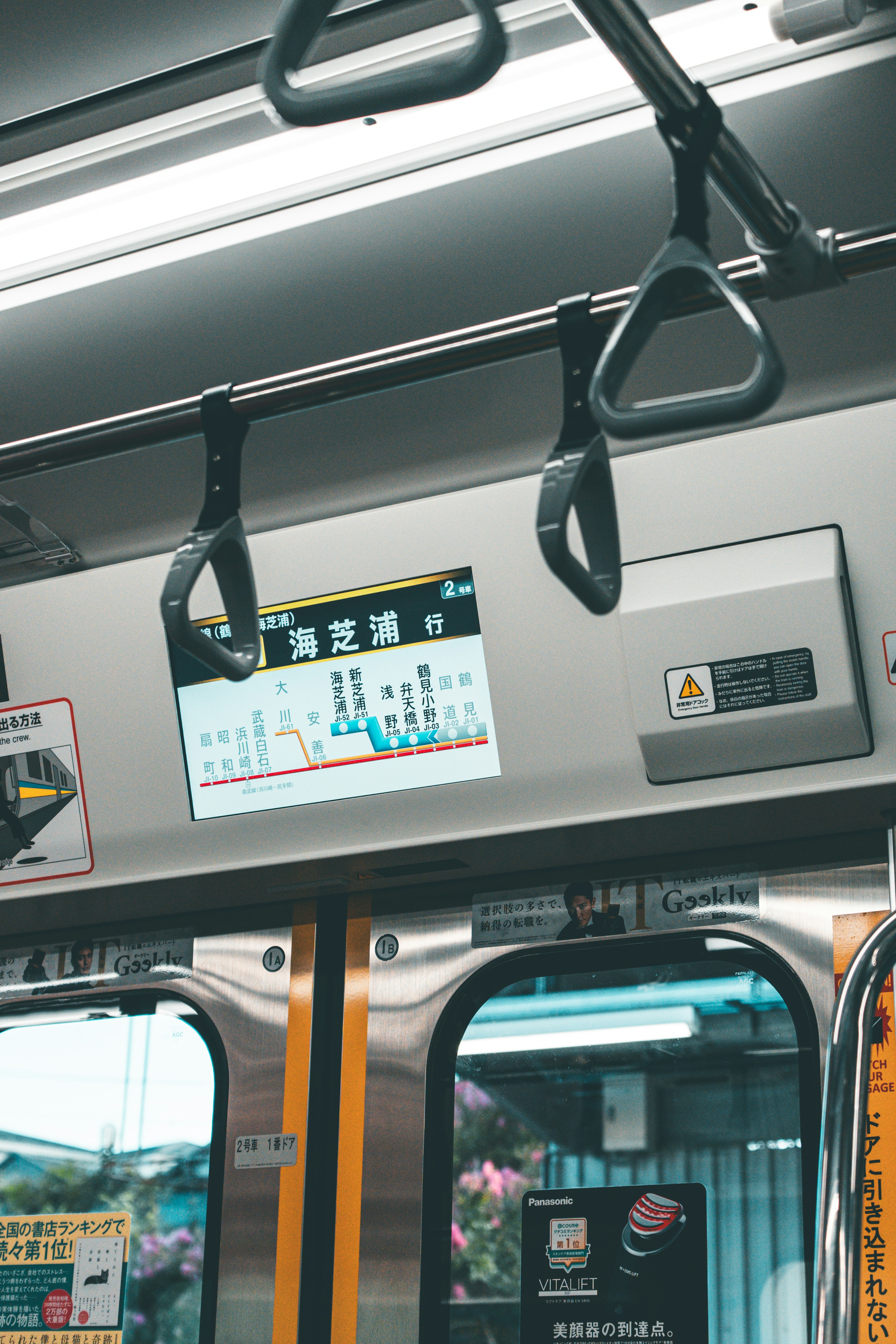 Interno di un treno con mancorrenti e schermo informativo