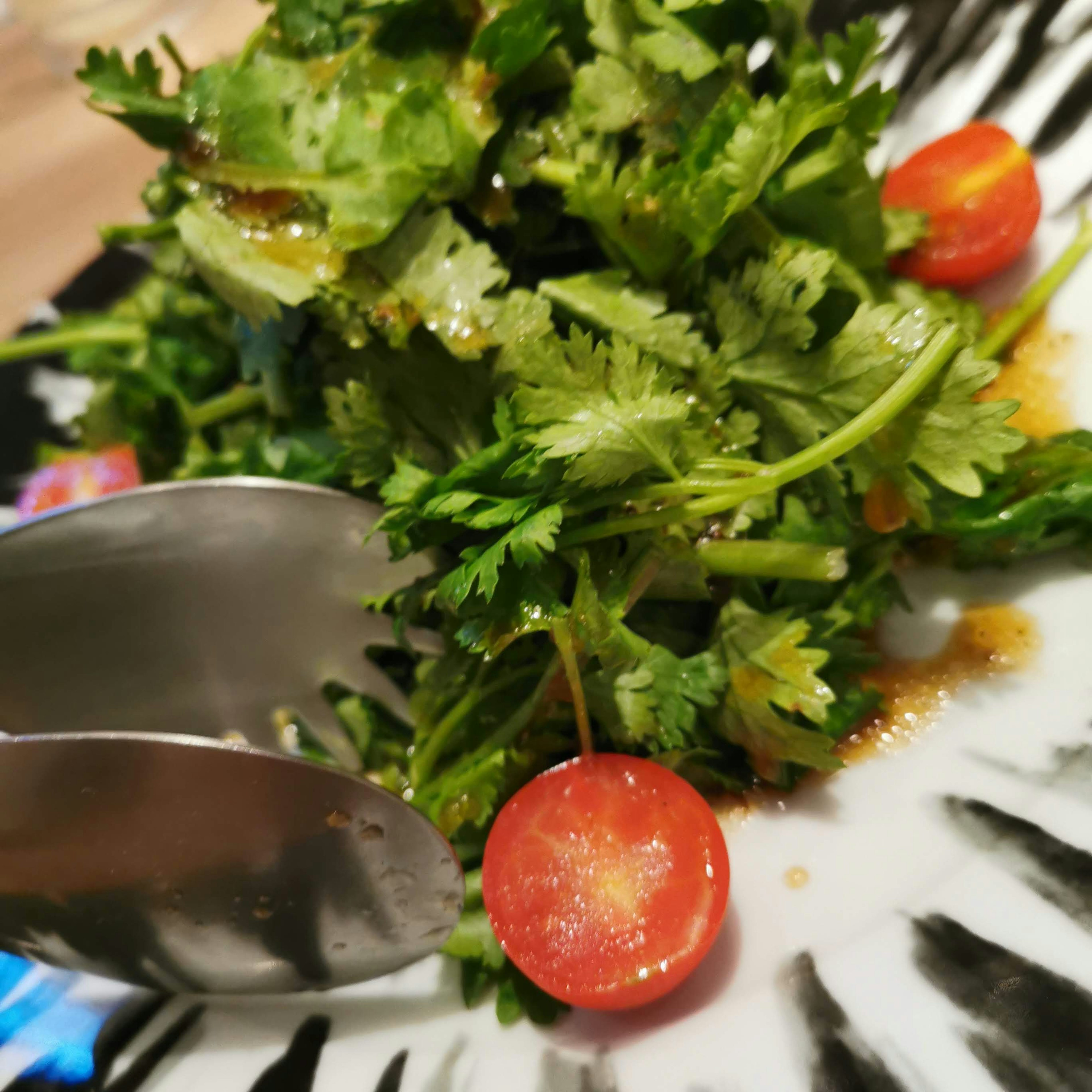 Salade de coriandre fraîche et tomates cerises prise avec des pinces