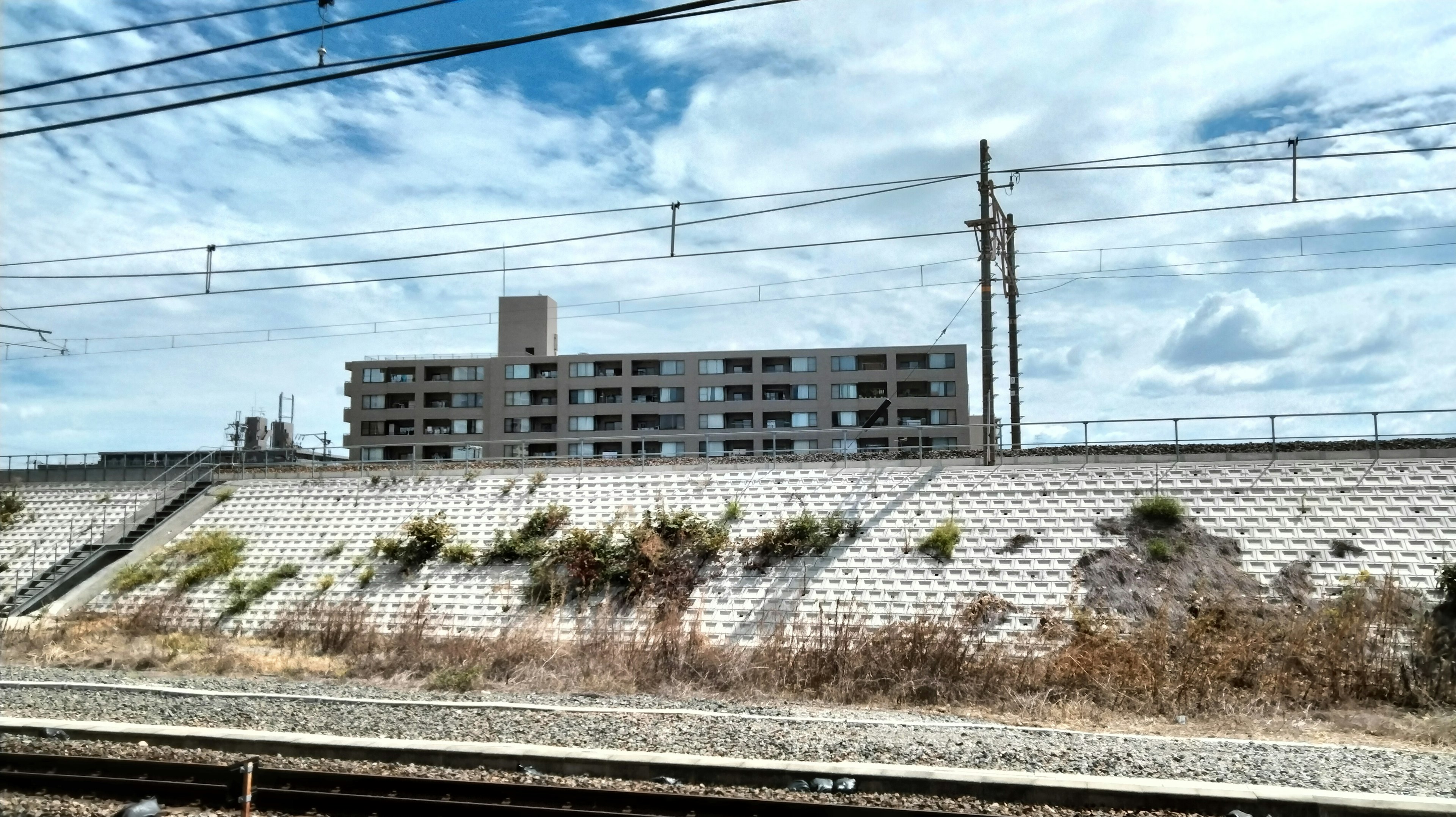 Abandoned apartment building beside railway tracks under a cloudy sky