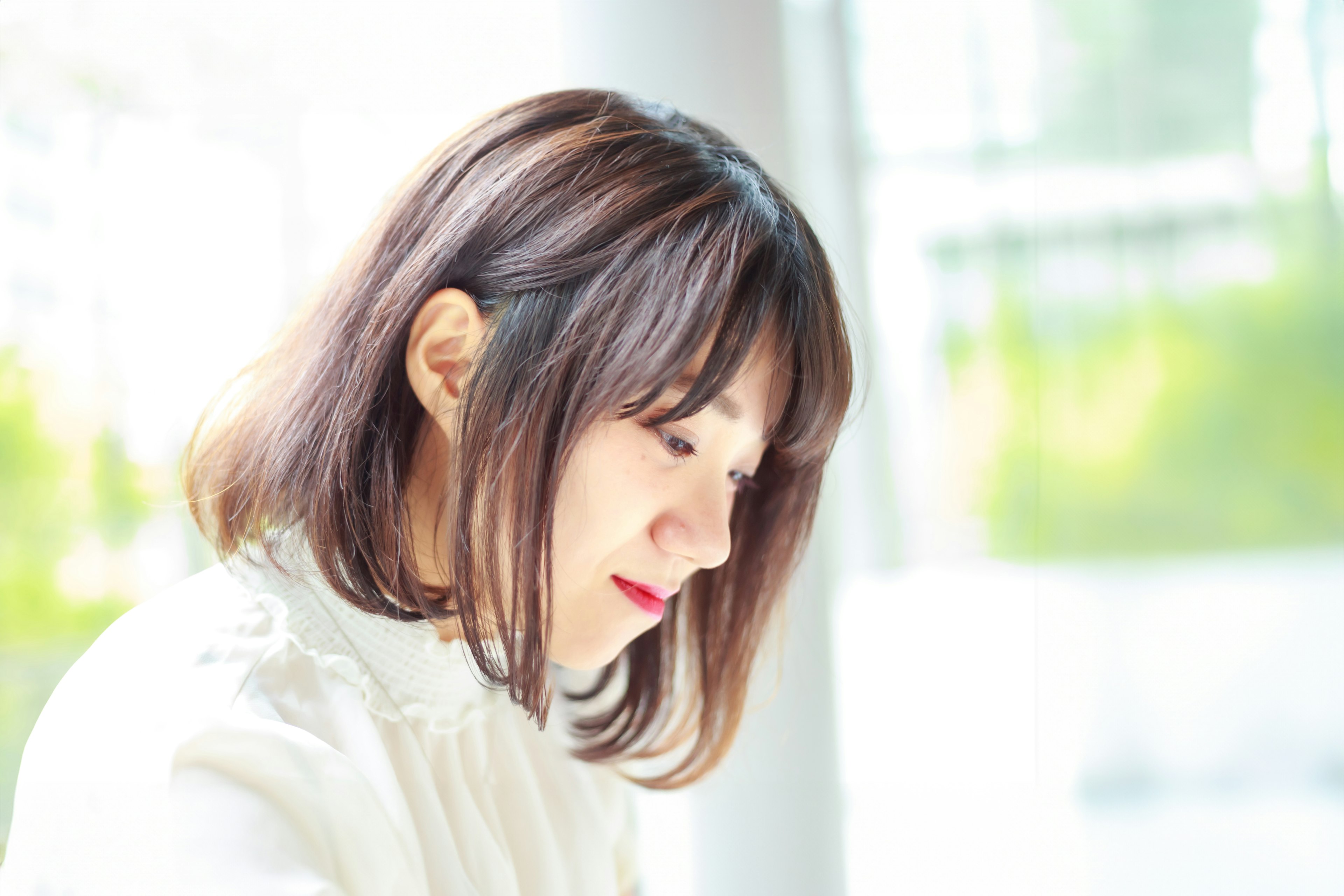 A woman thoughtfully concentrating in a white outfit with natural light in the background