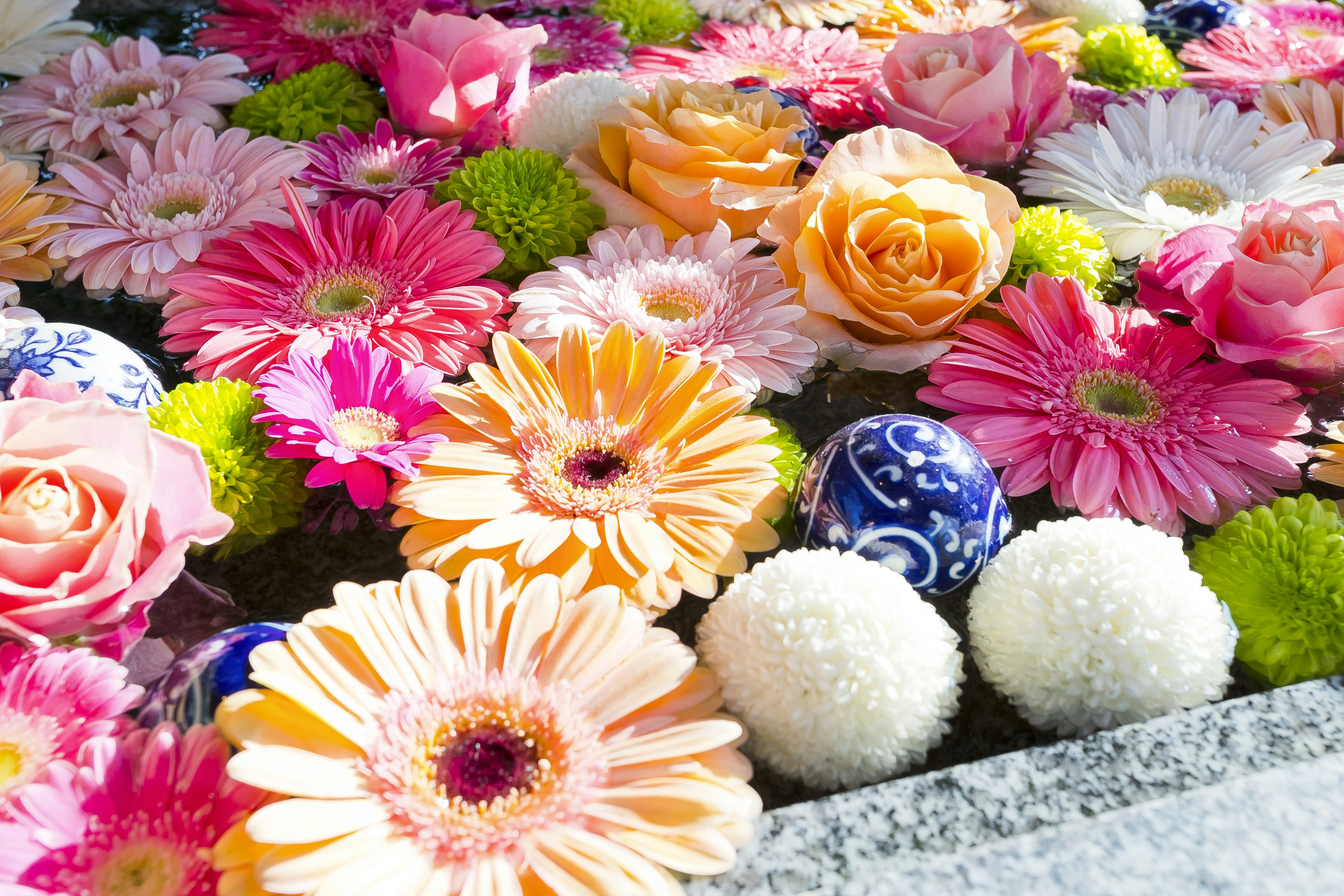 Arrangement floral vibrant avec des roses, des gerberas et des sphères décoratives