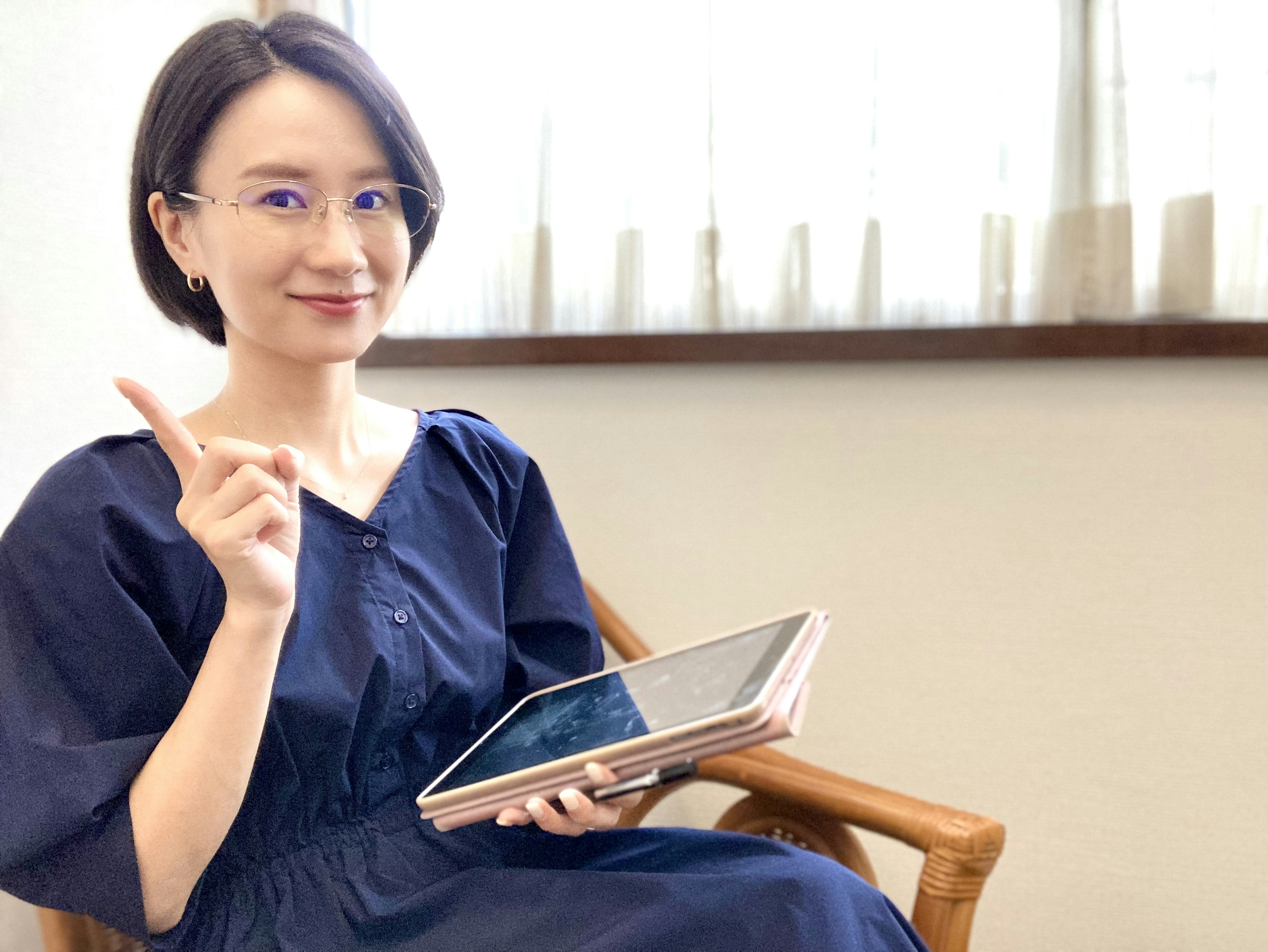 A woman holding a tablet smiling and pointing in a bright room