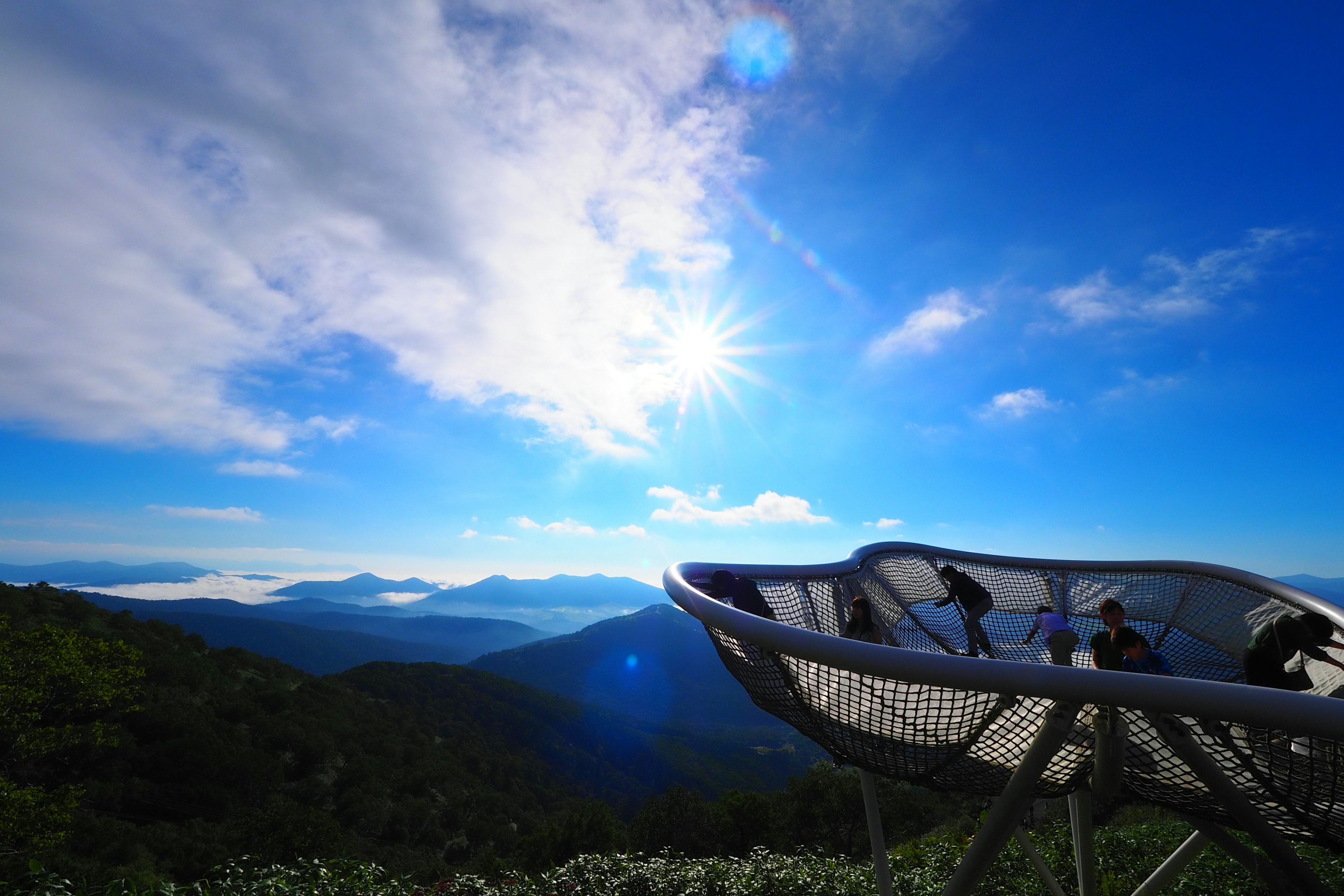 Pemandangan gunung panorama di bawah langit biru dan matahari dengan platform pengamatan