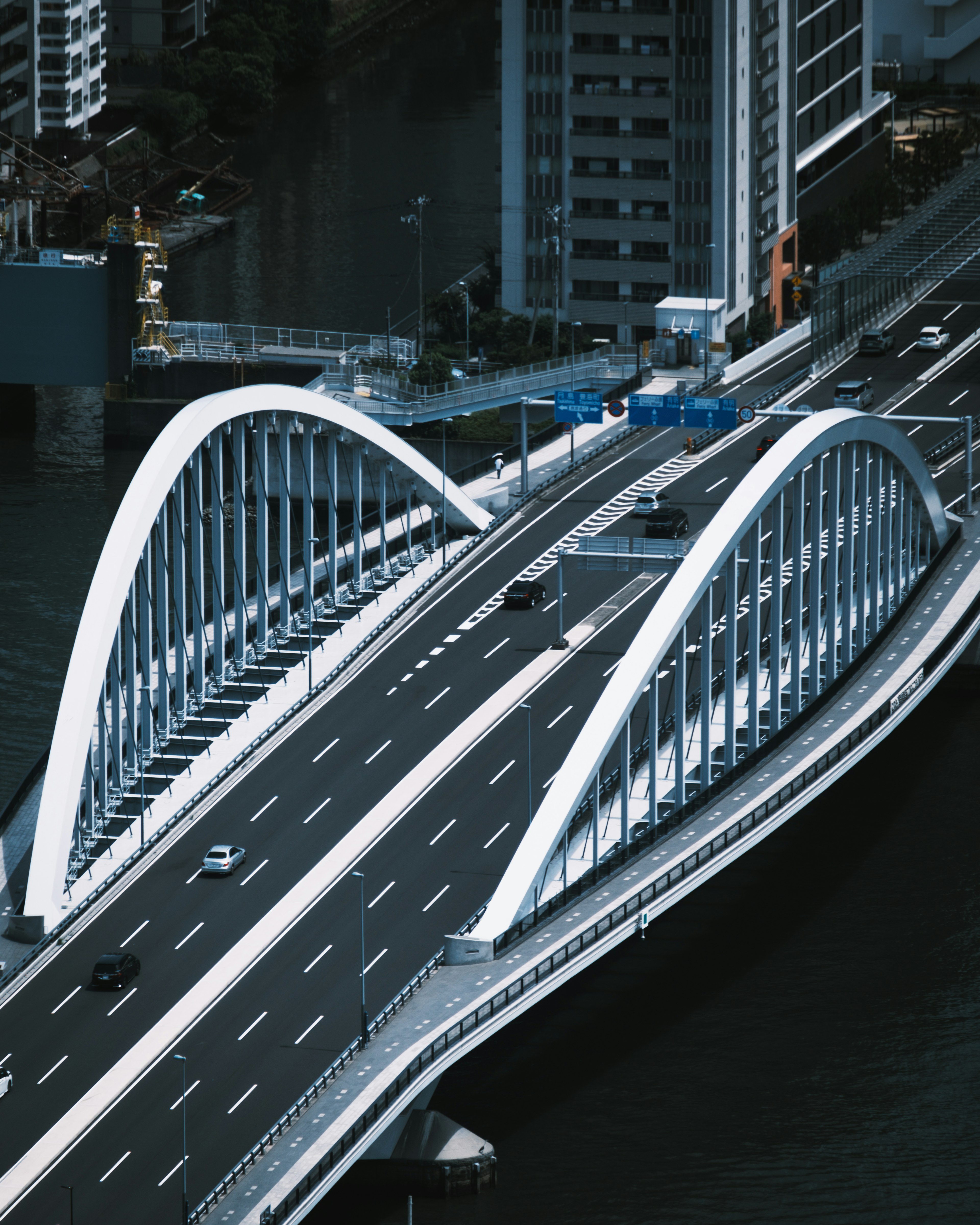 Modern arch bridge with flowing traffic and cityscape