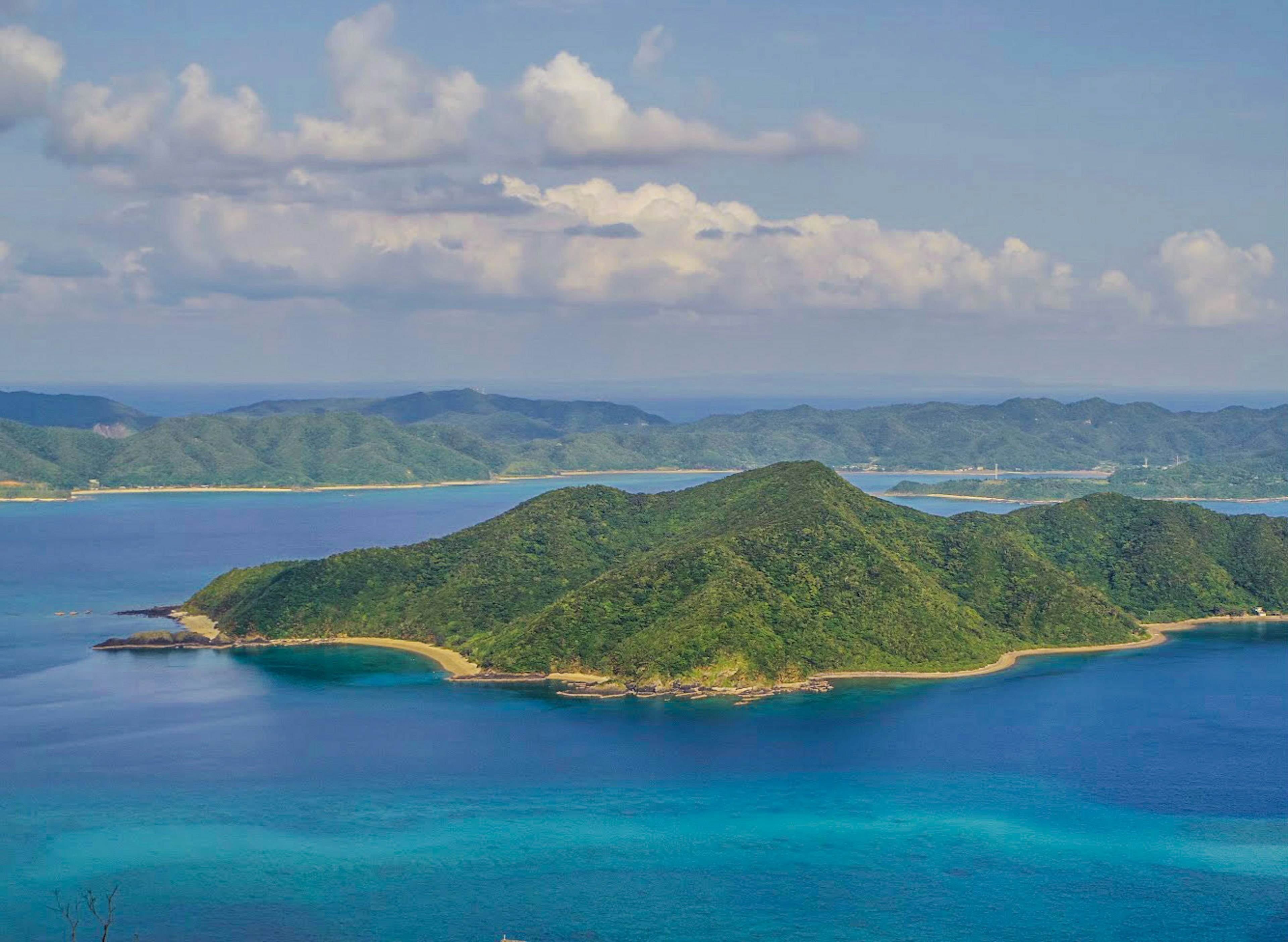 Vista aerea di un'isola con una collina verde circondata da acque blu