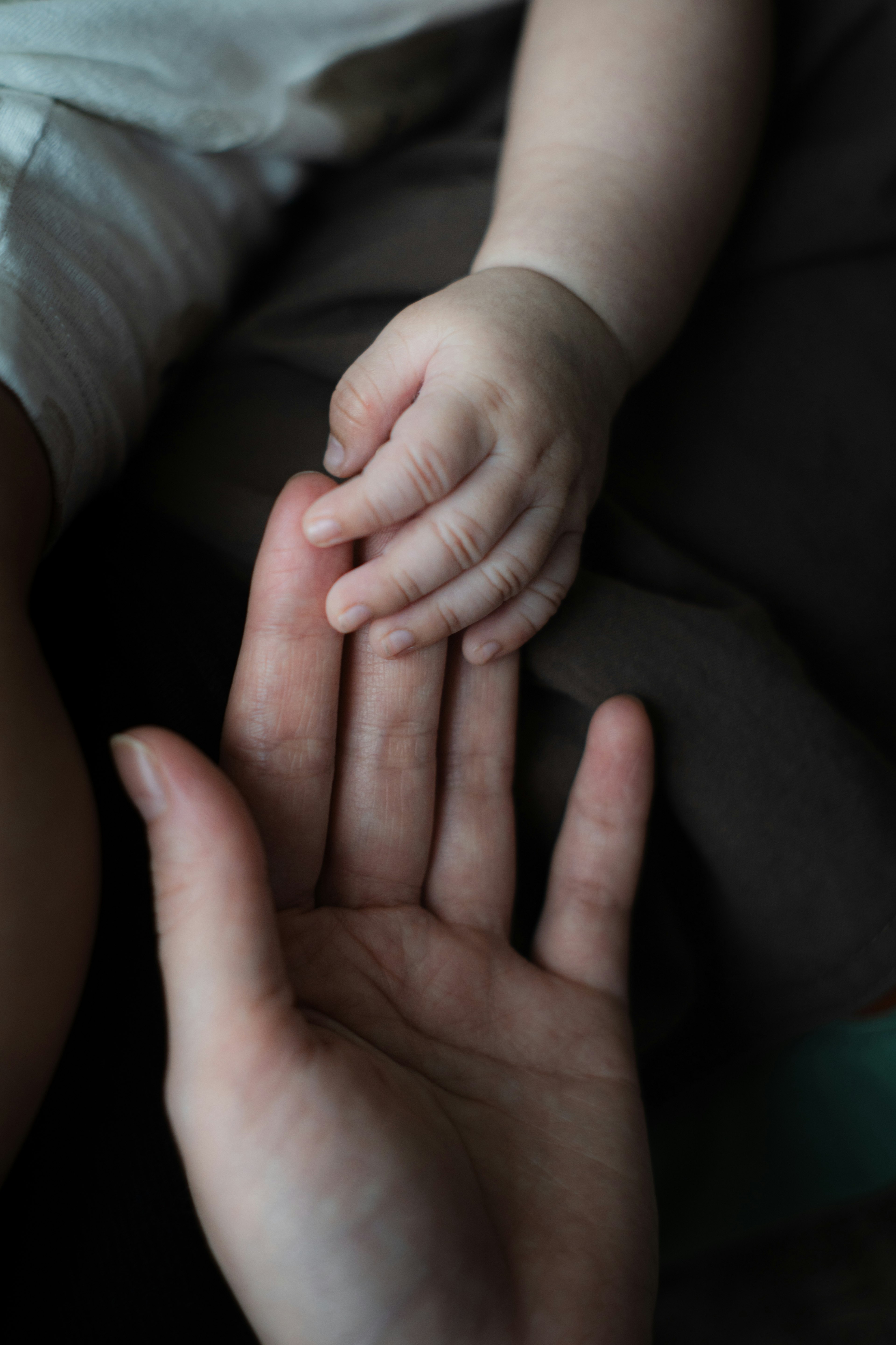 Eine Babyhand berührt eine Hand eines Erwachsenen