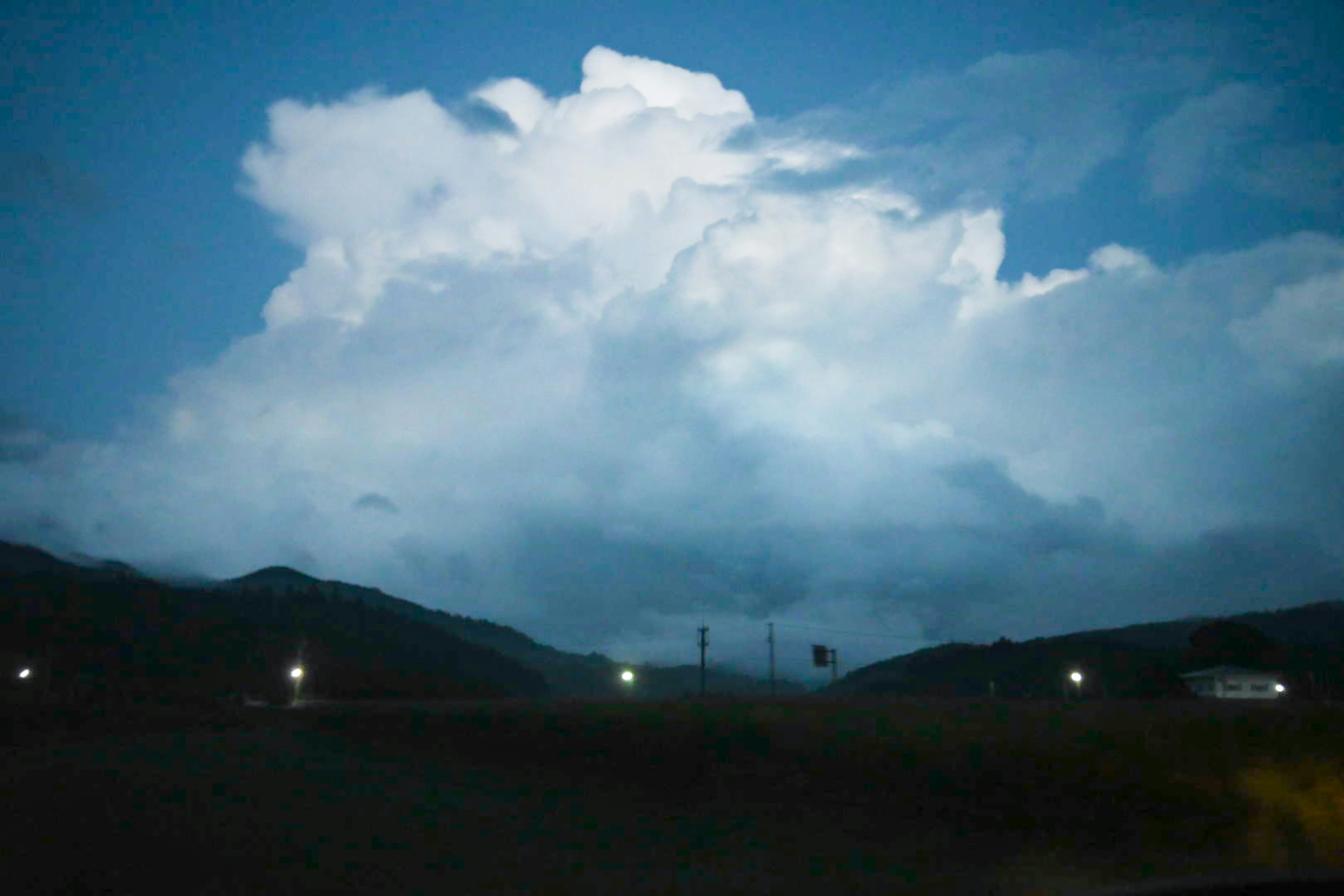 Cielo nocturno con nubes y montañas distantes