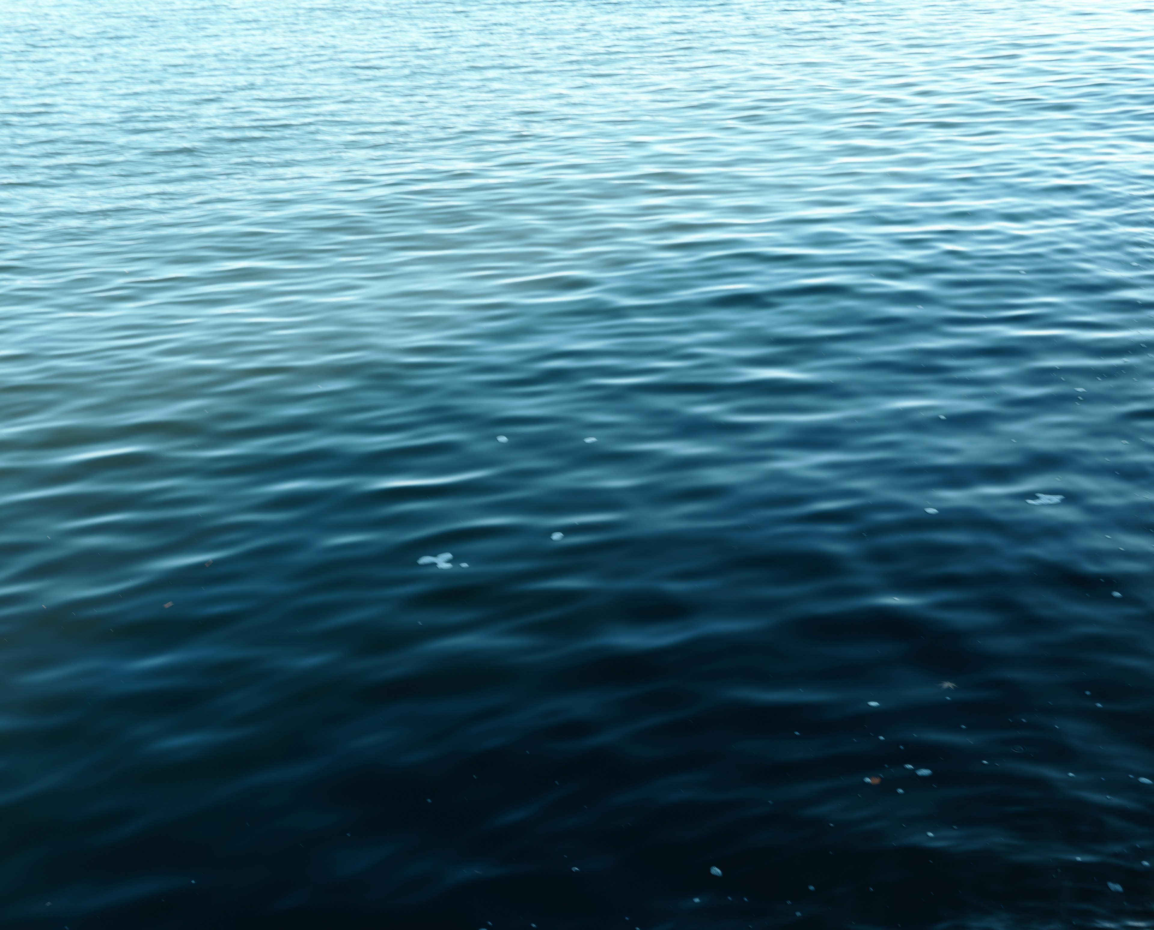 Ruhige Wasseroberfläche mit Wellen in tiefblauen Farbtönen