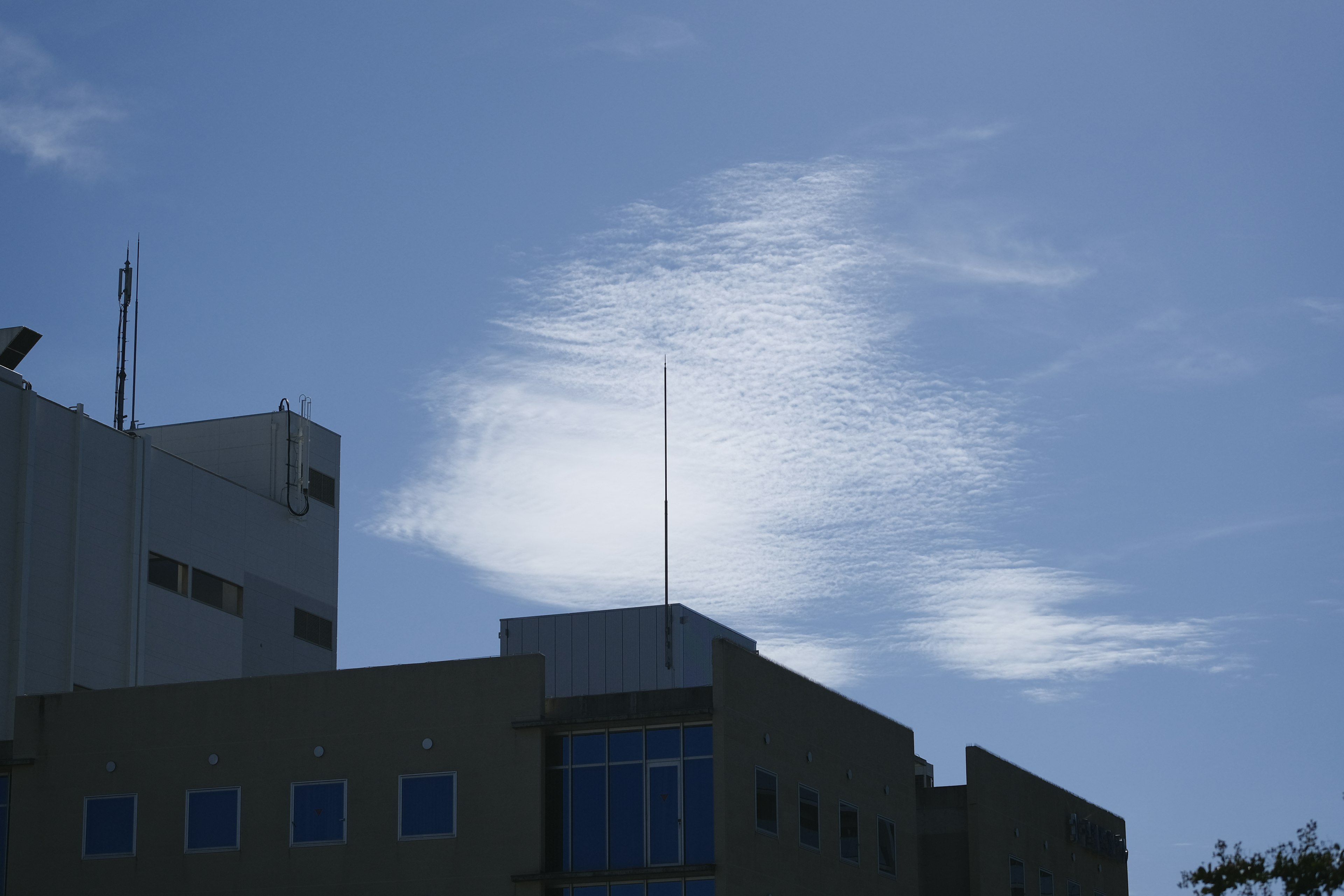 Unique cloud formation against a blue sky with part of a building