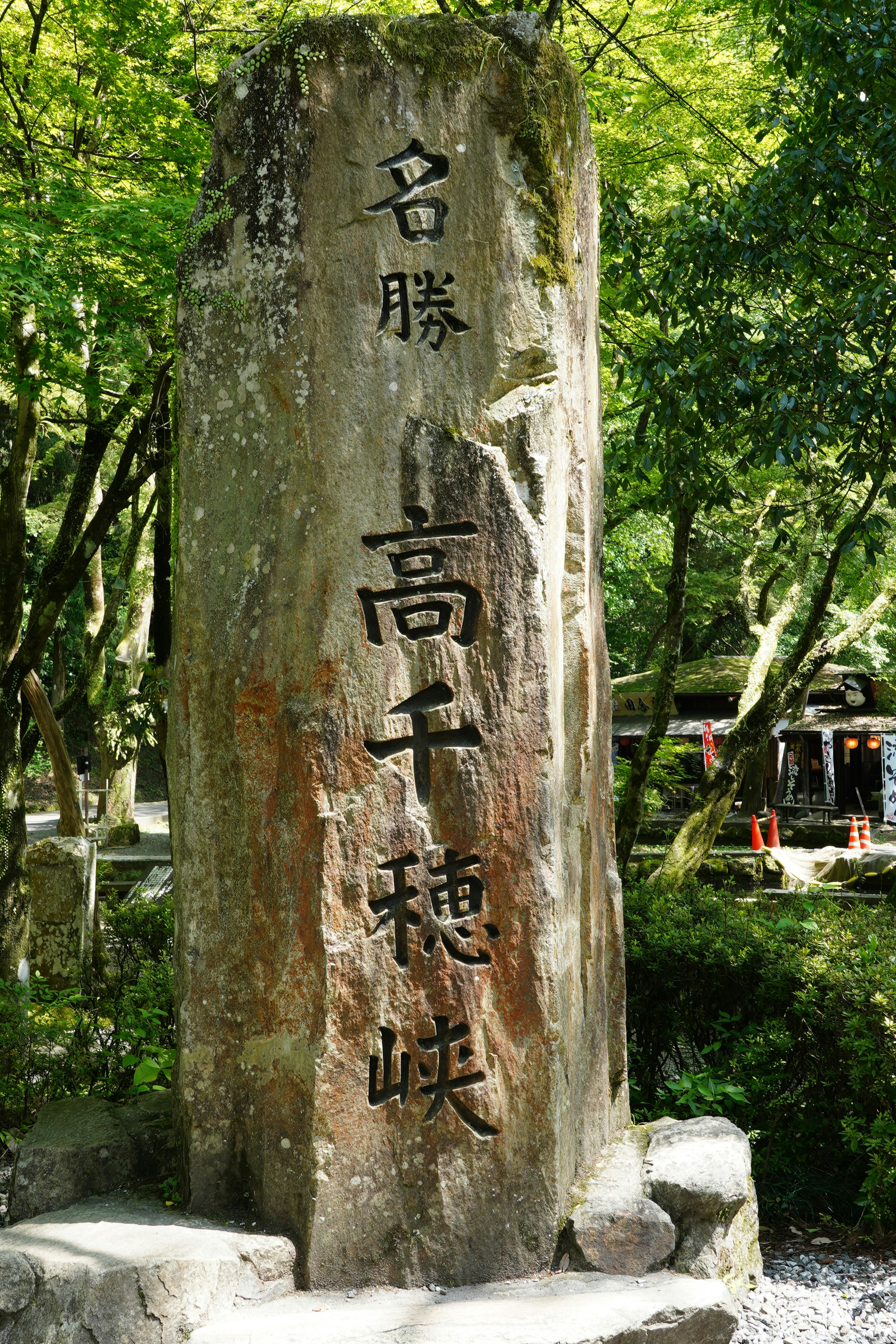 A large stone monument with engraved characters surrounded by greenery