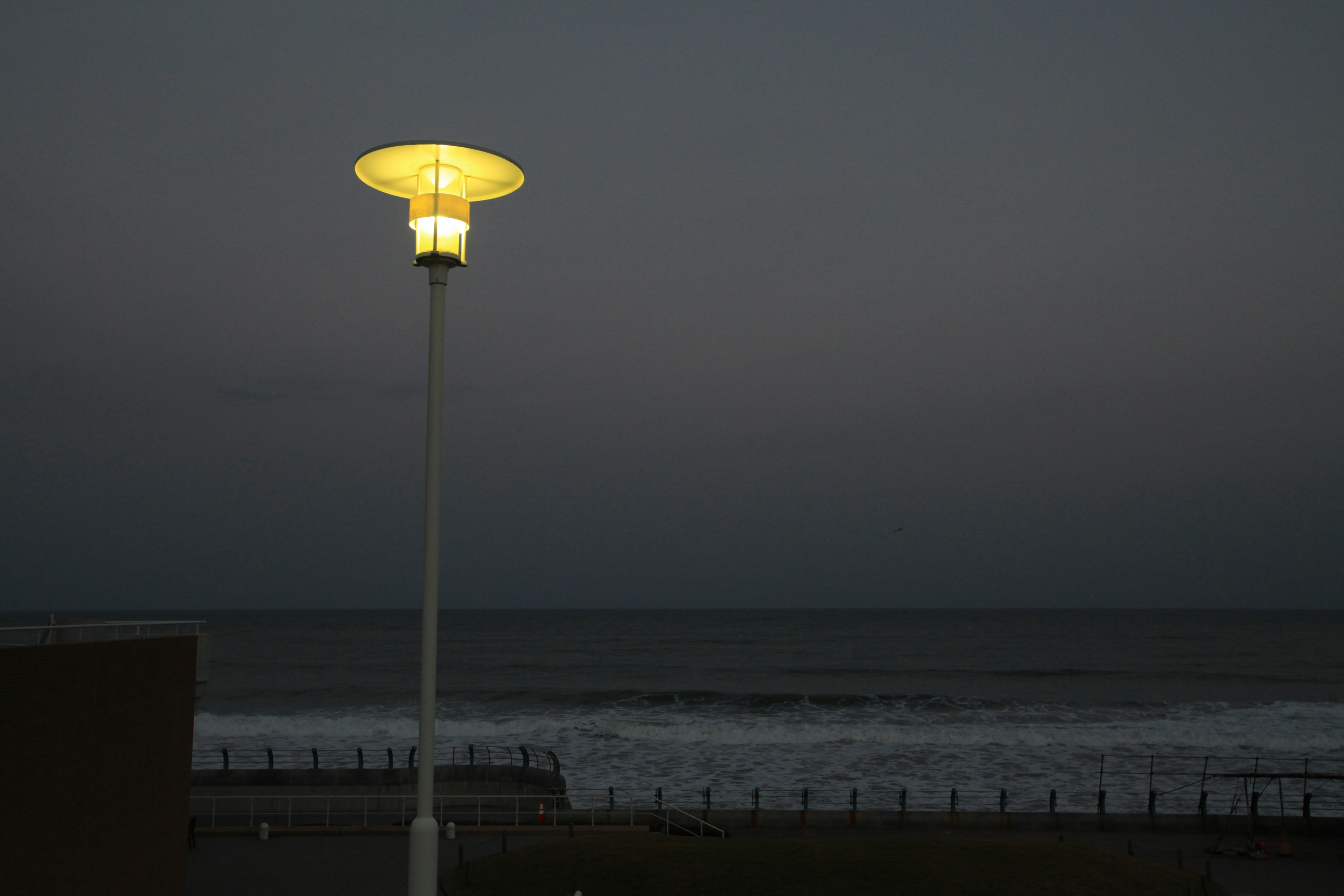 Farola brillante en la playa de noche con cielo oscuro