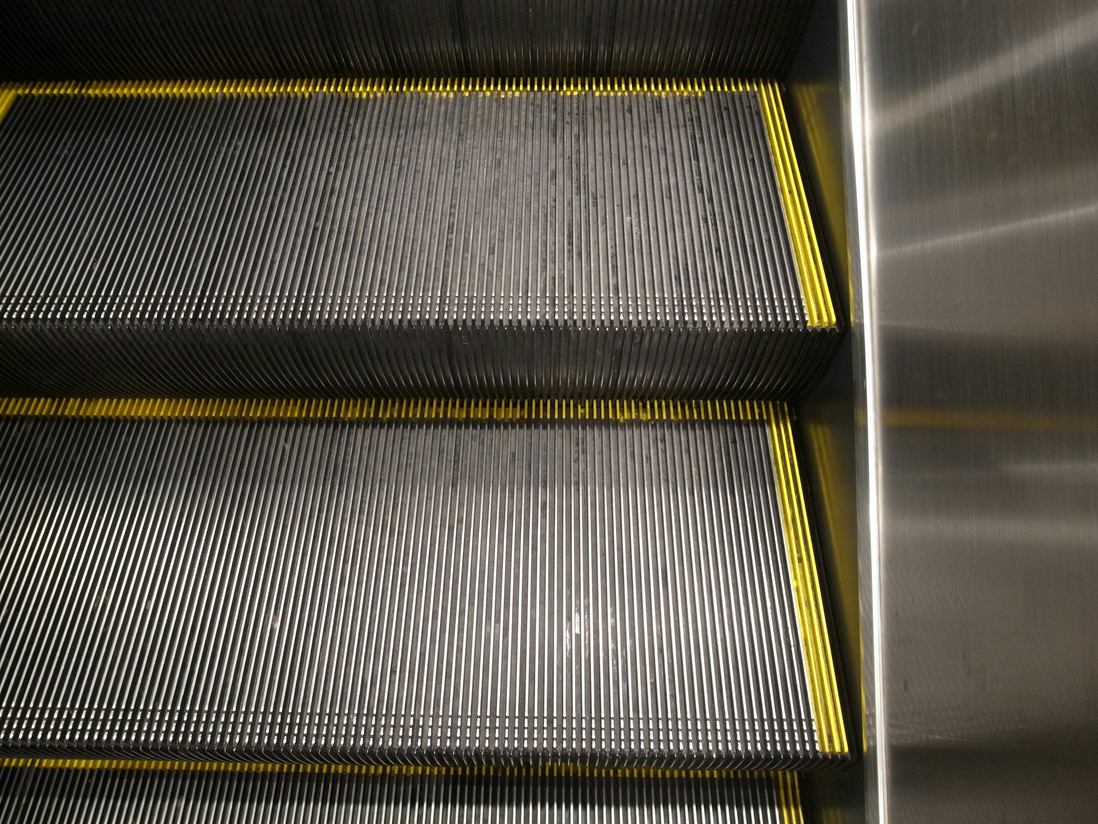 Primer plano de los escalones de una escalera mecánica con borde amarillo