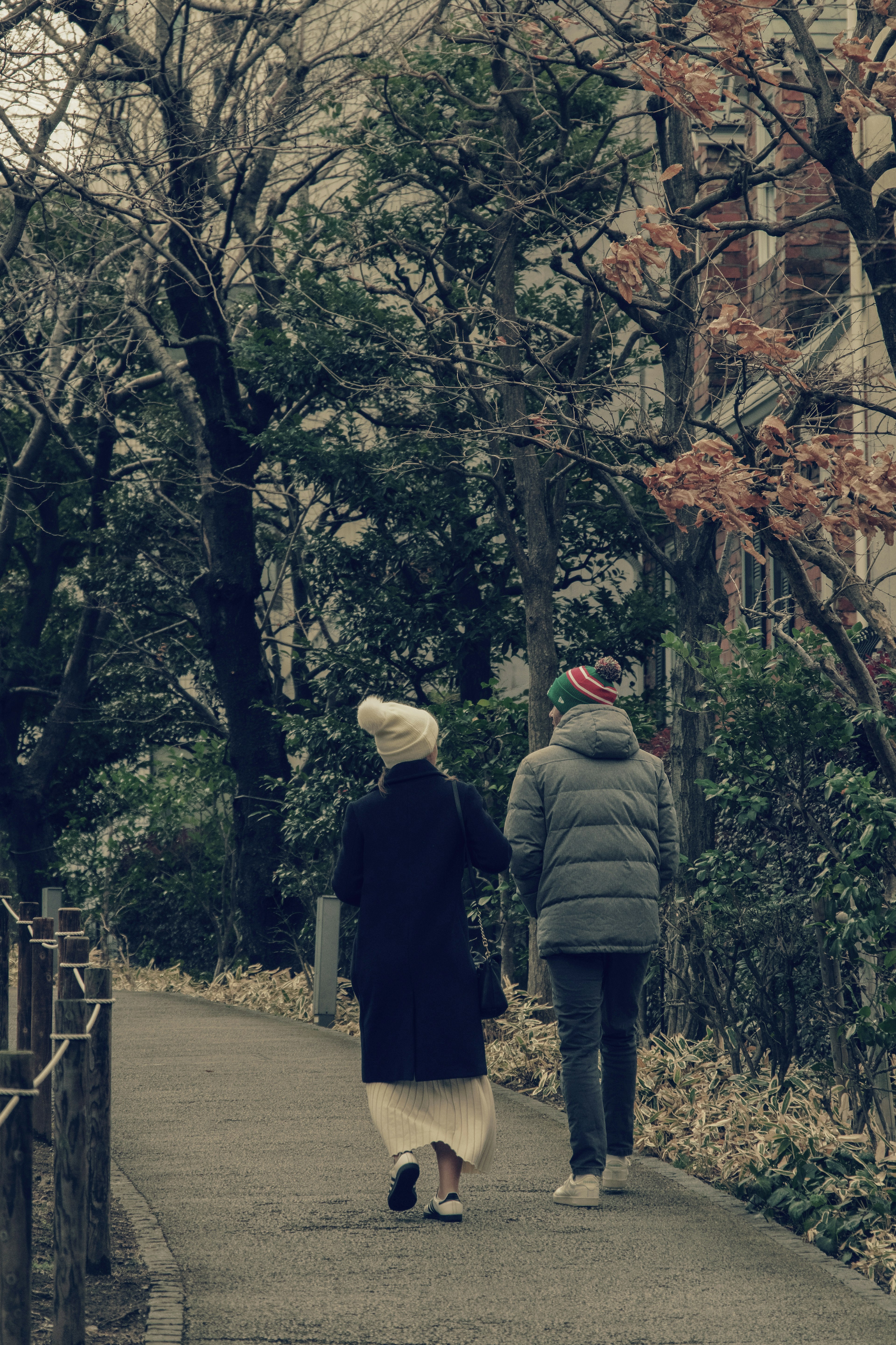 Two individuals walking along a path surrounded by trees