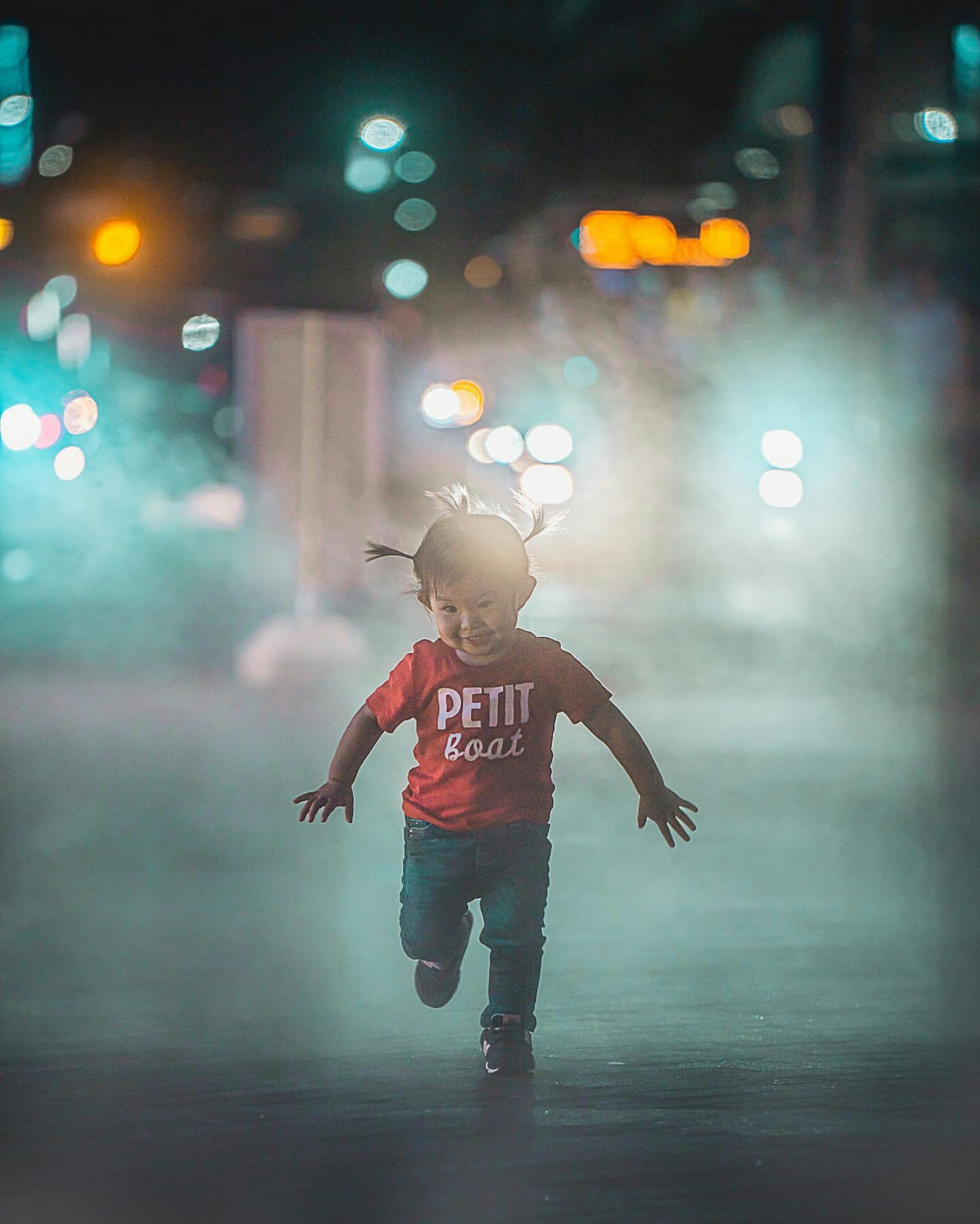 Anak berlari di kabut mengenakan kaos merah