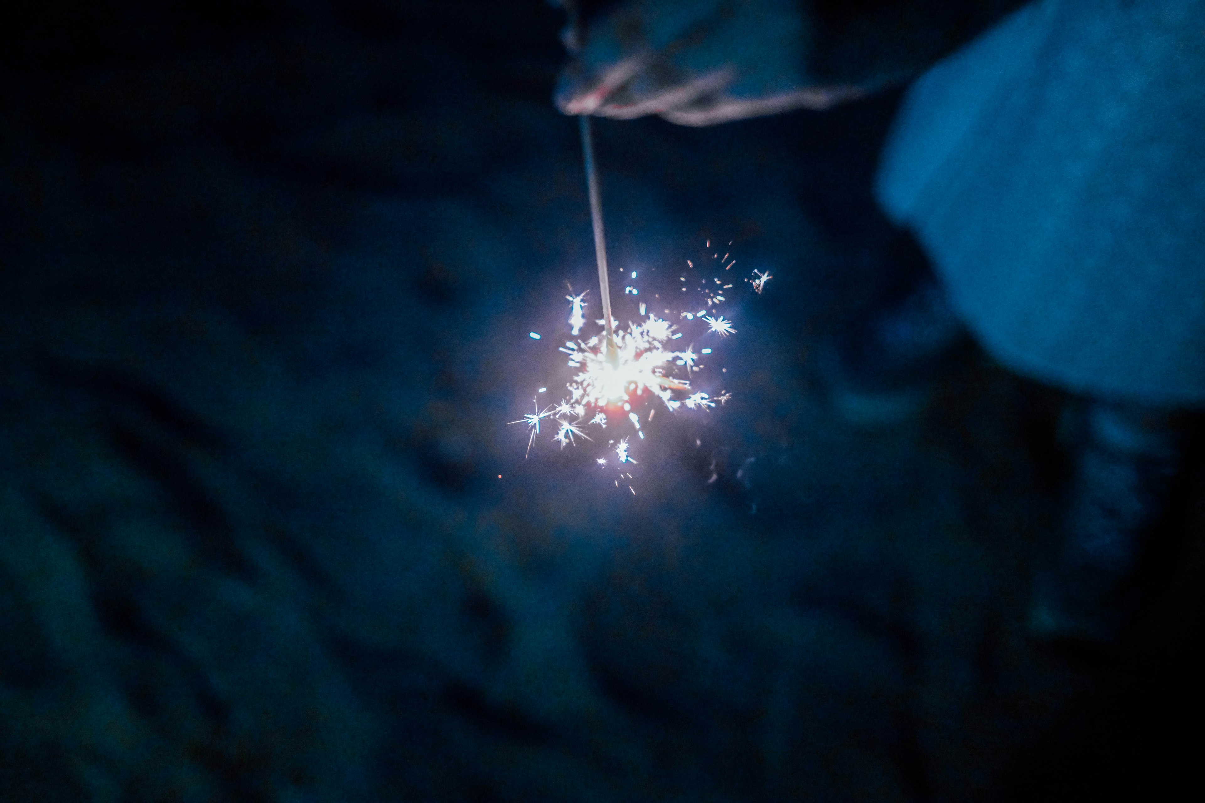 Un fuego artificial sostenido en mano brillando en la oscuridad