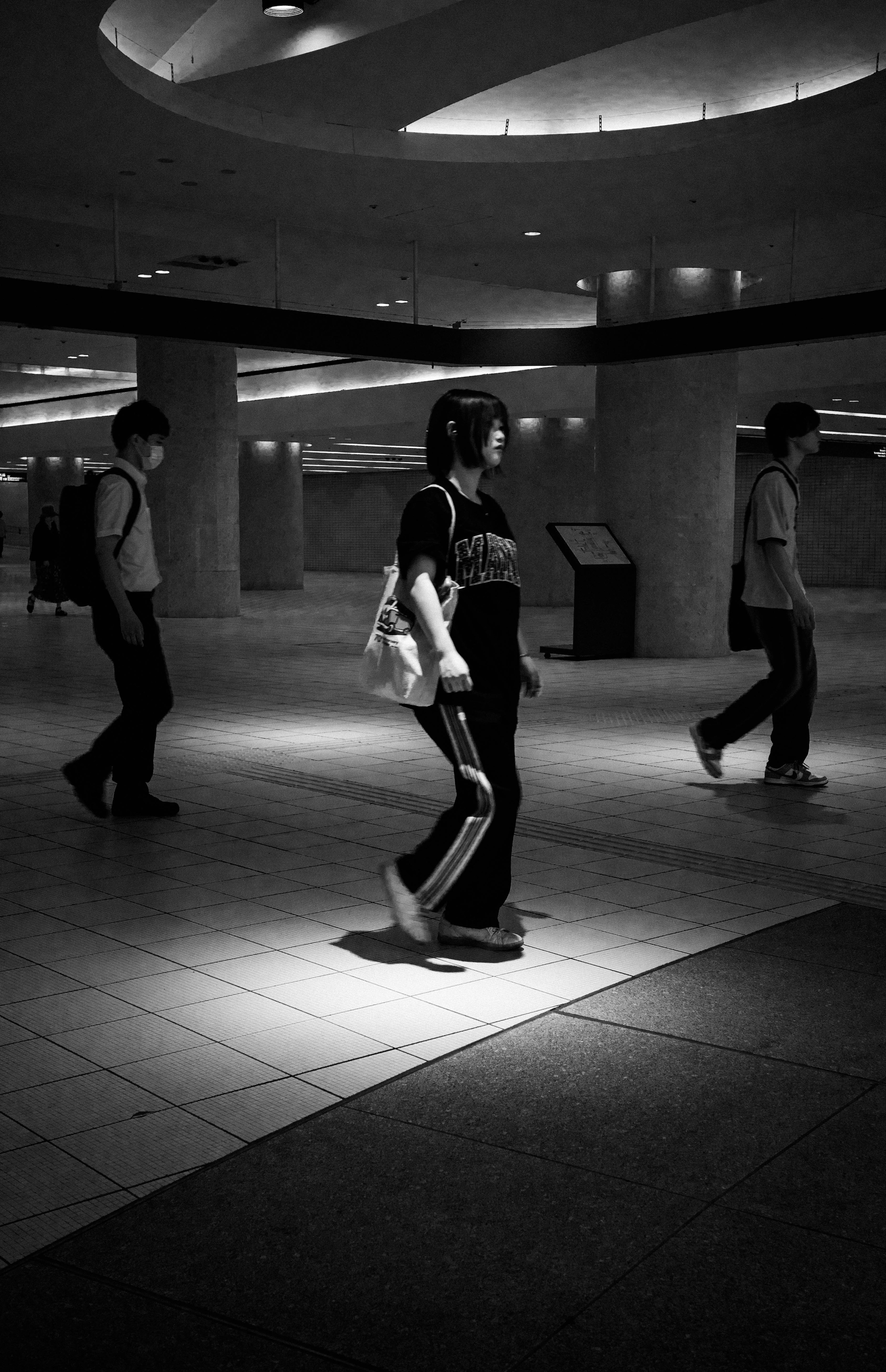 Silhouettes of people walking in a dark underground passage with bright spotlight contrast