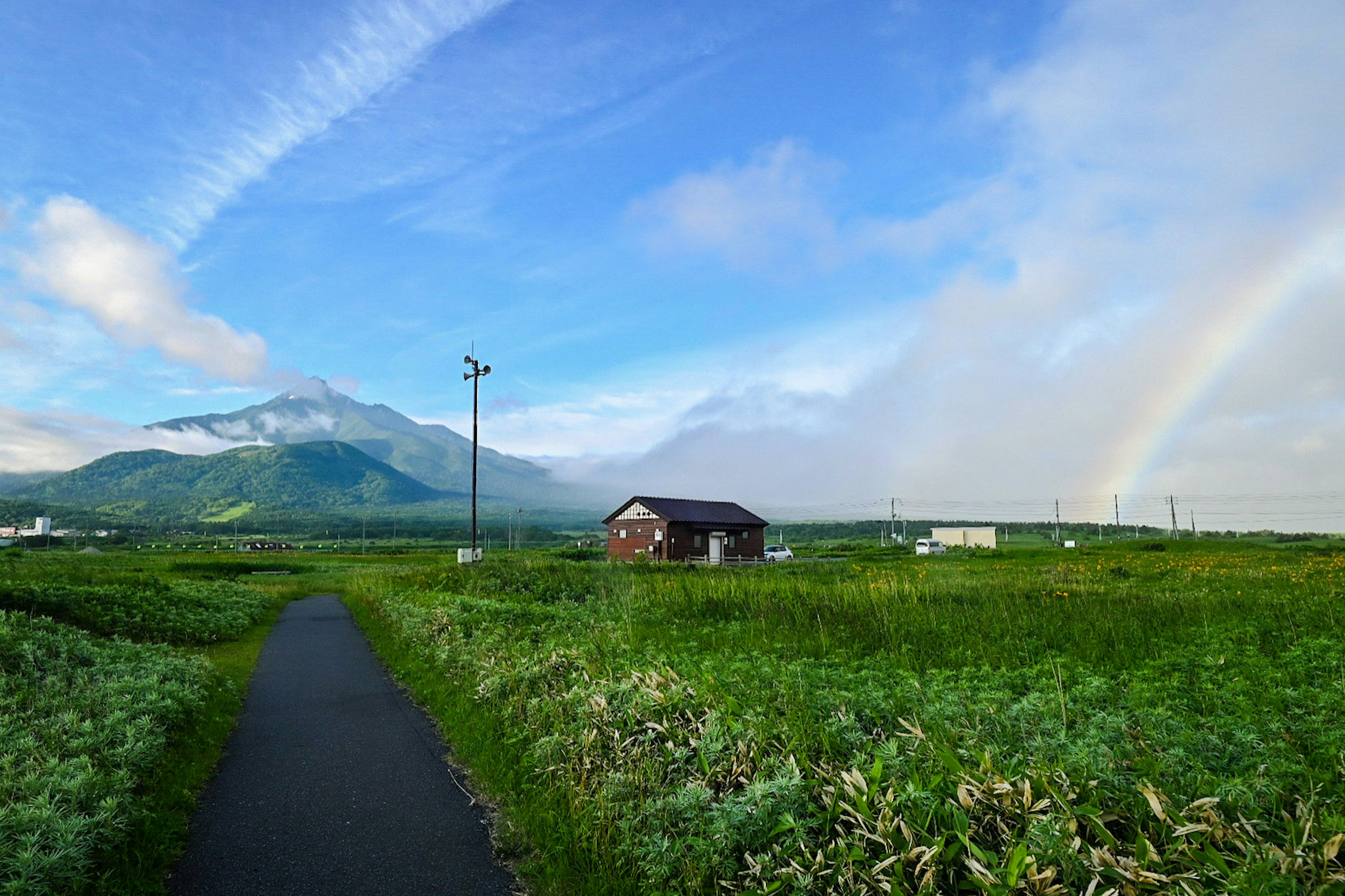 绿田间小路的风景，背景是山和彩虹